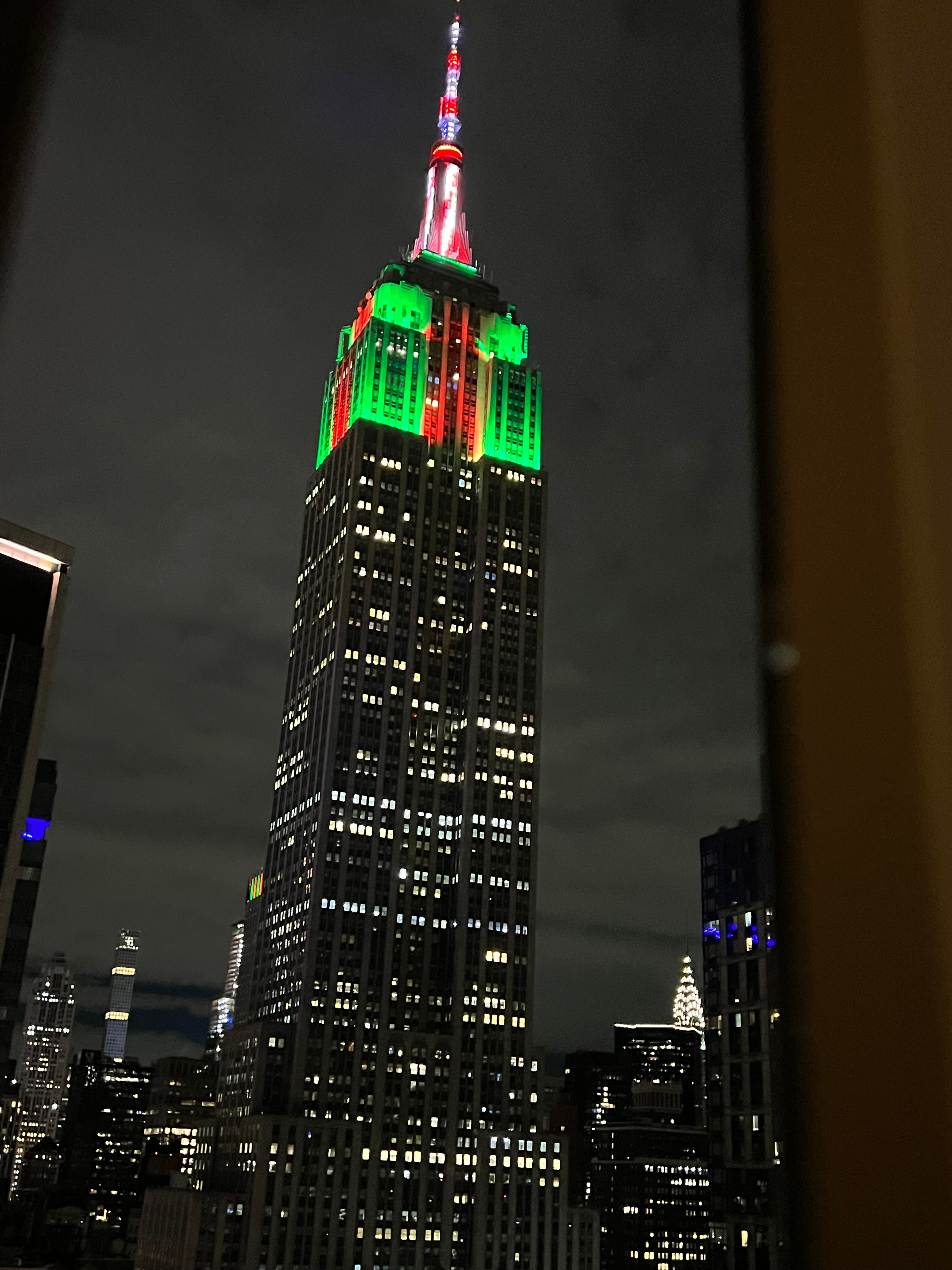 Empire State Building lit up with red and green lights at night in NYC