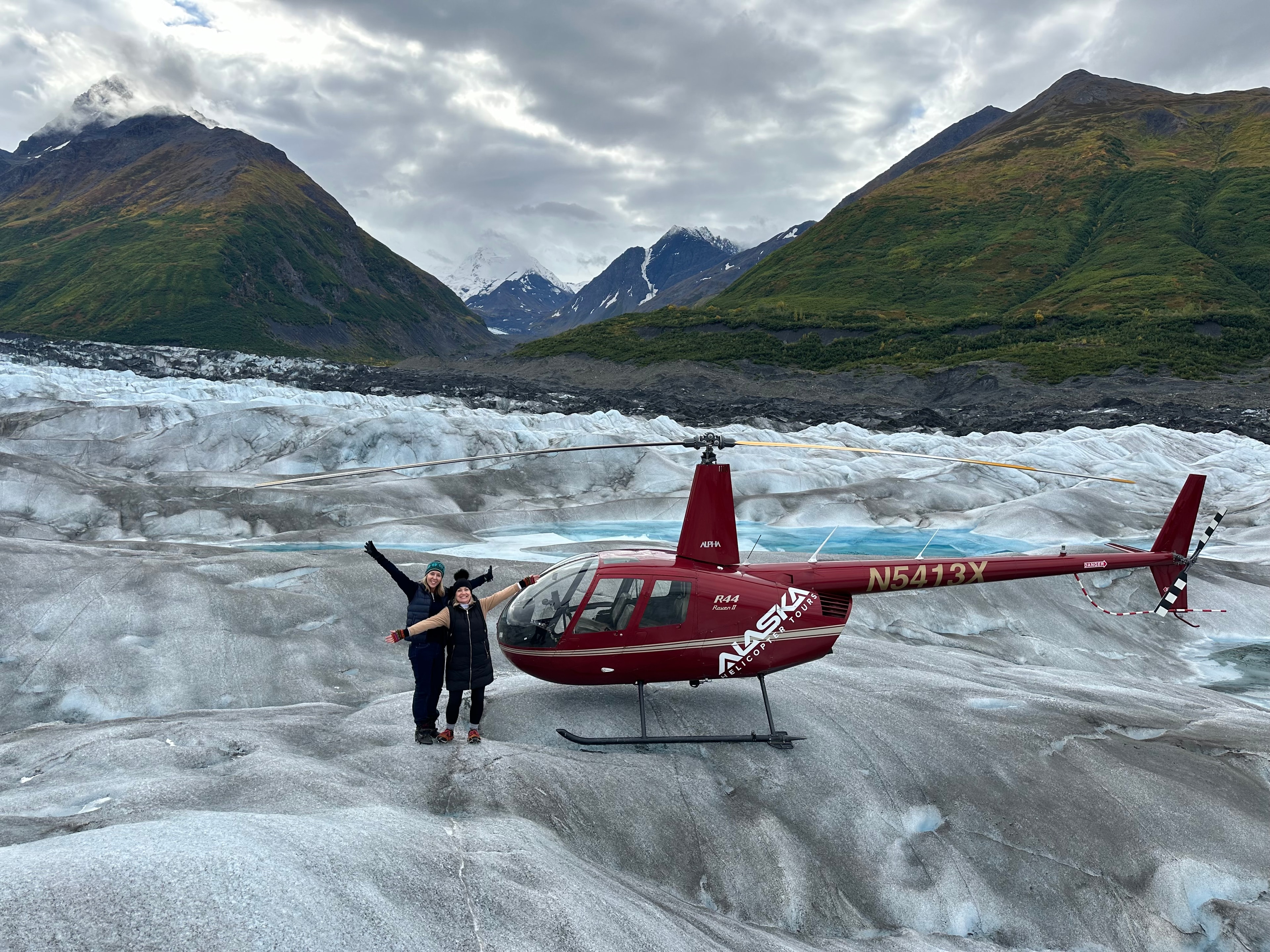 Advisor and friend standing on an icy landscape beside a red helicopter