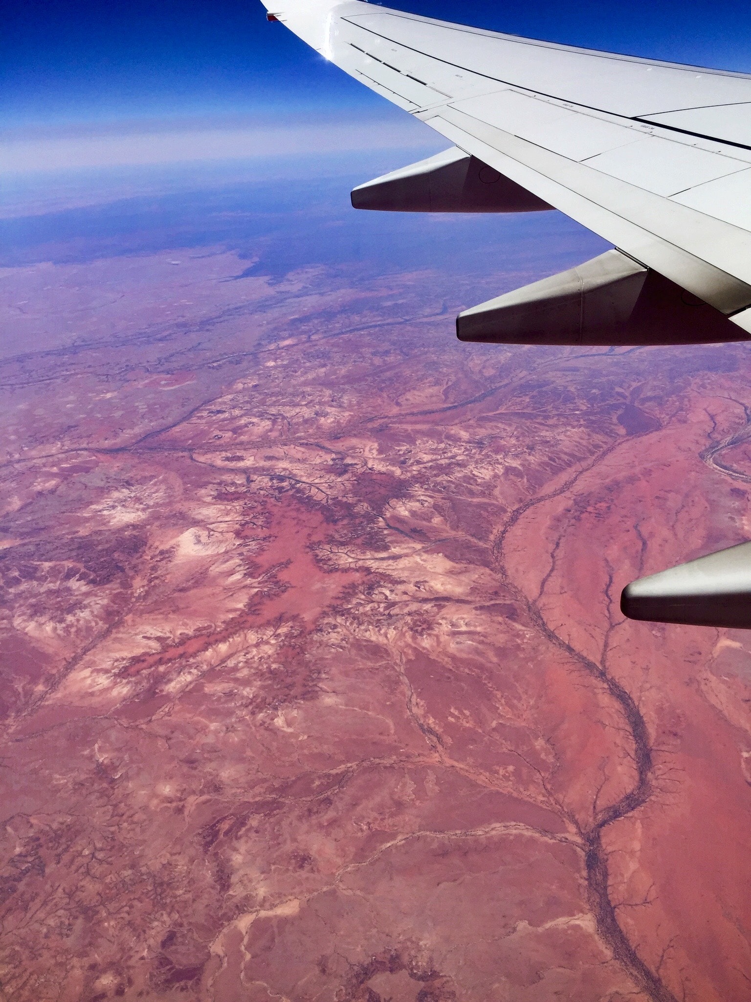 View of a desert canyon landscape and wing of a plane seen from high above the ground