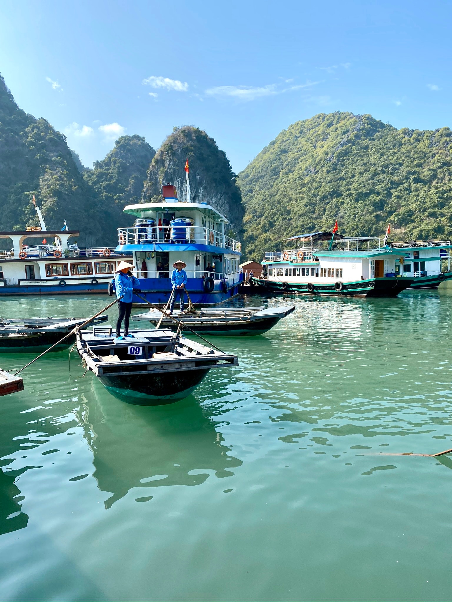 View of guides steering small fishing boats with lush jungle mountains in the background