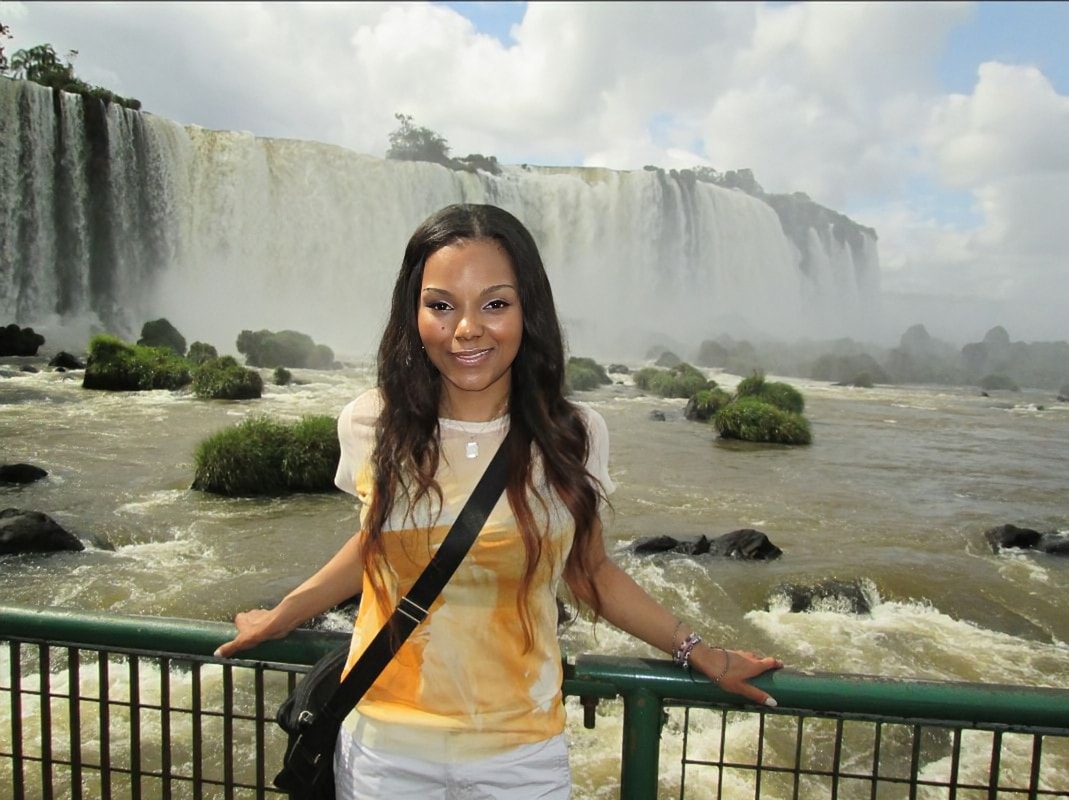 Advisor leaning against a railing besides an enormous waterfall