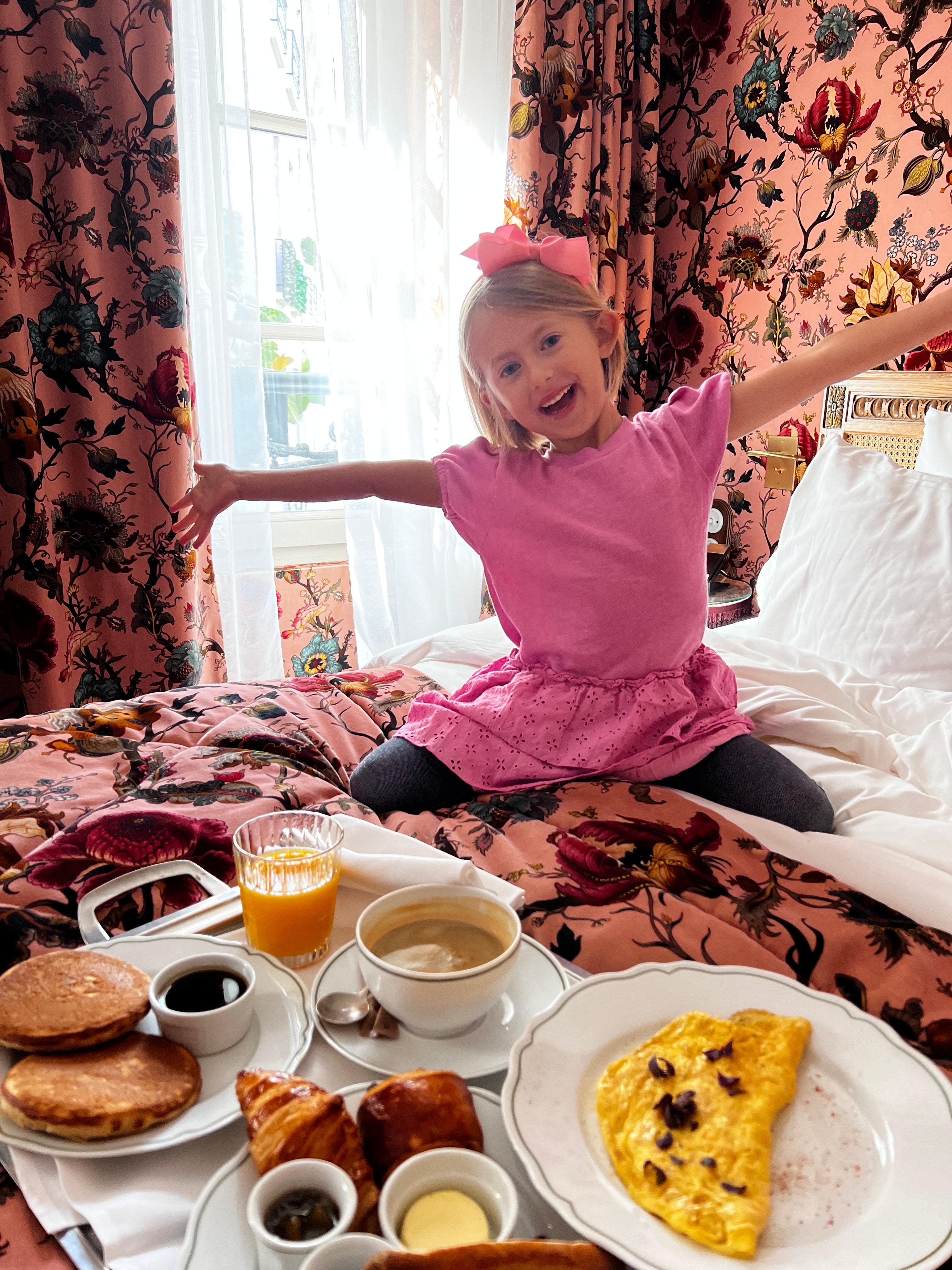 Advisor’s daughter sitting on a hotel room bed with a breakfast spread before her