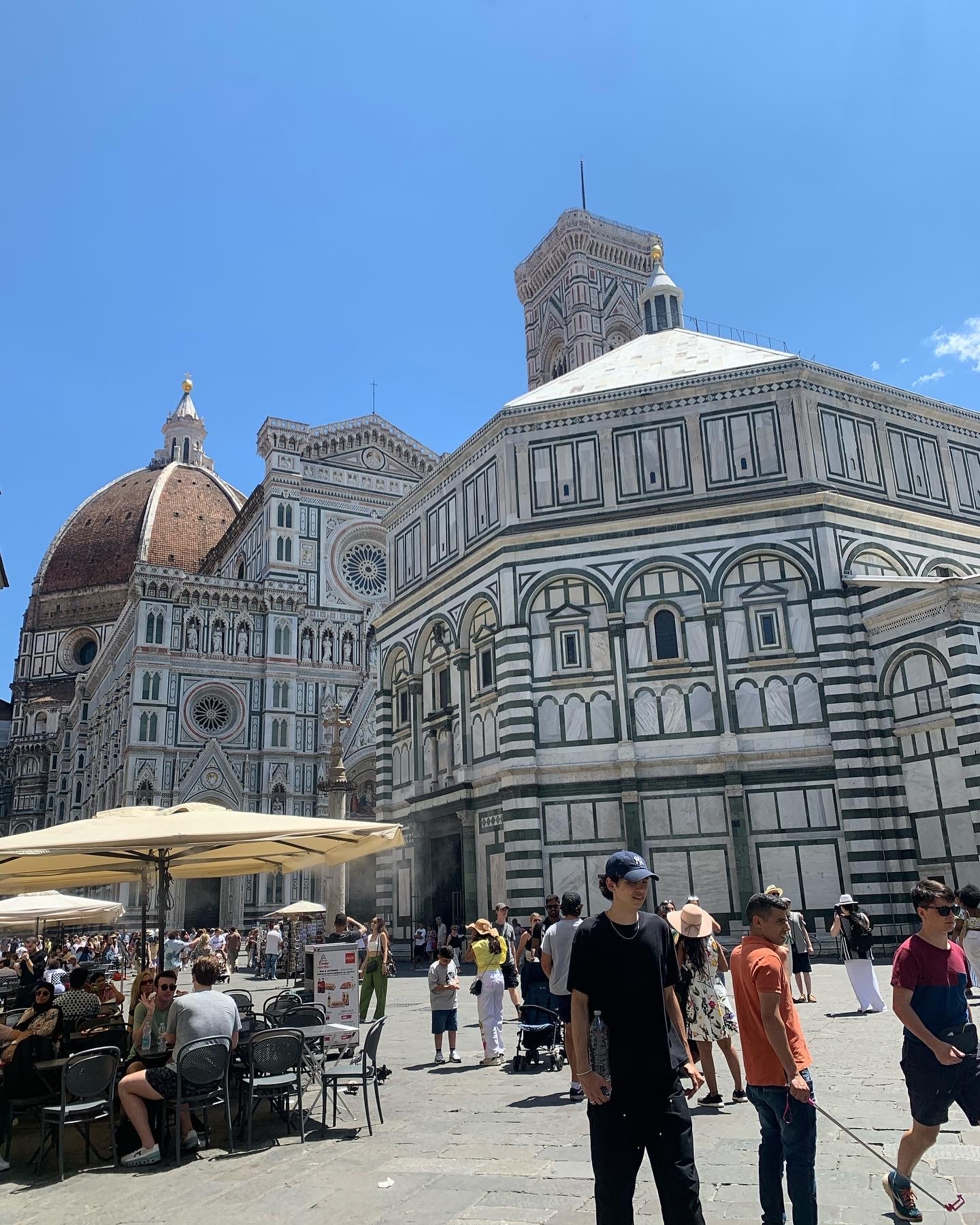 View of pedestrians walking around beautiful buildings and a domed cathedral on a clear day