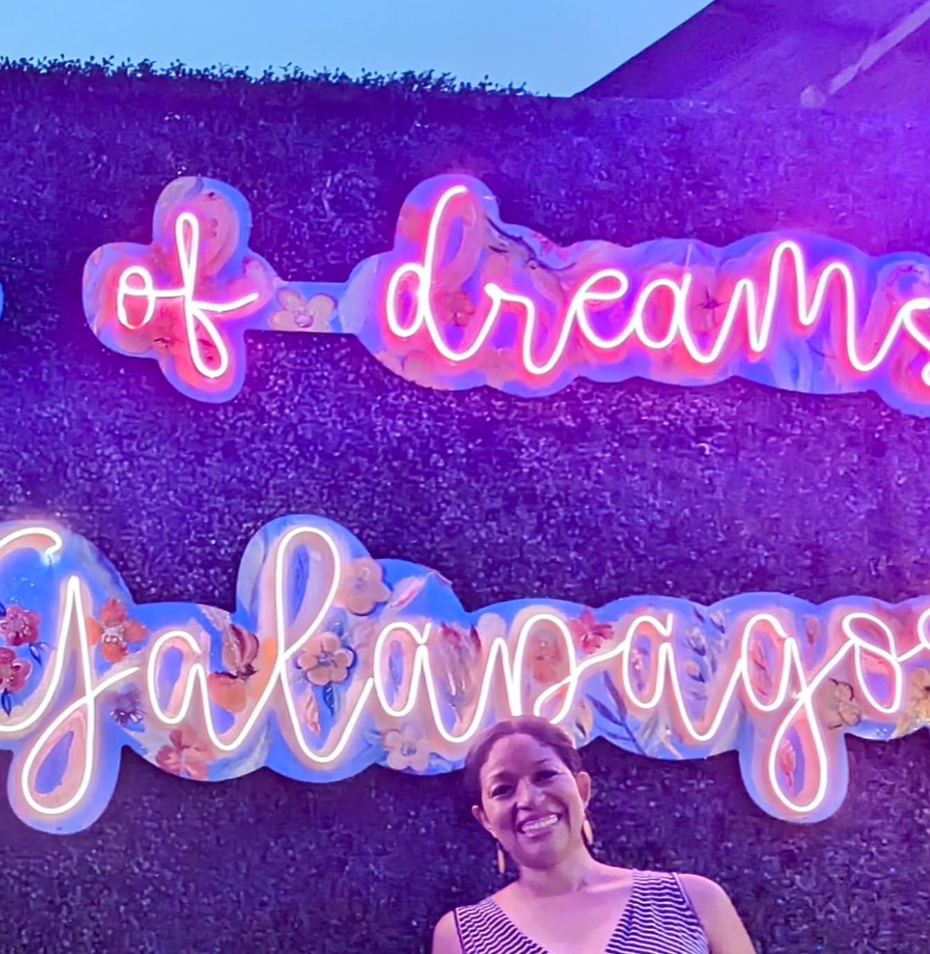 Advisor smiling in front of a neon sign in the Galapagos