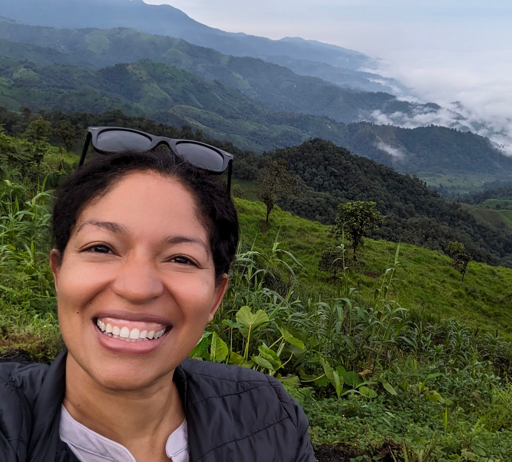 Advisor taking a selfie with a lush mountain valley behind her on a cloudy day