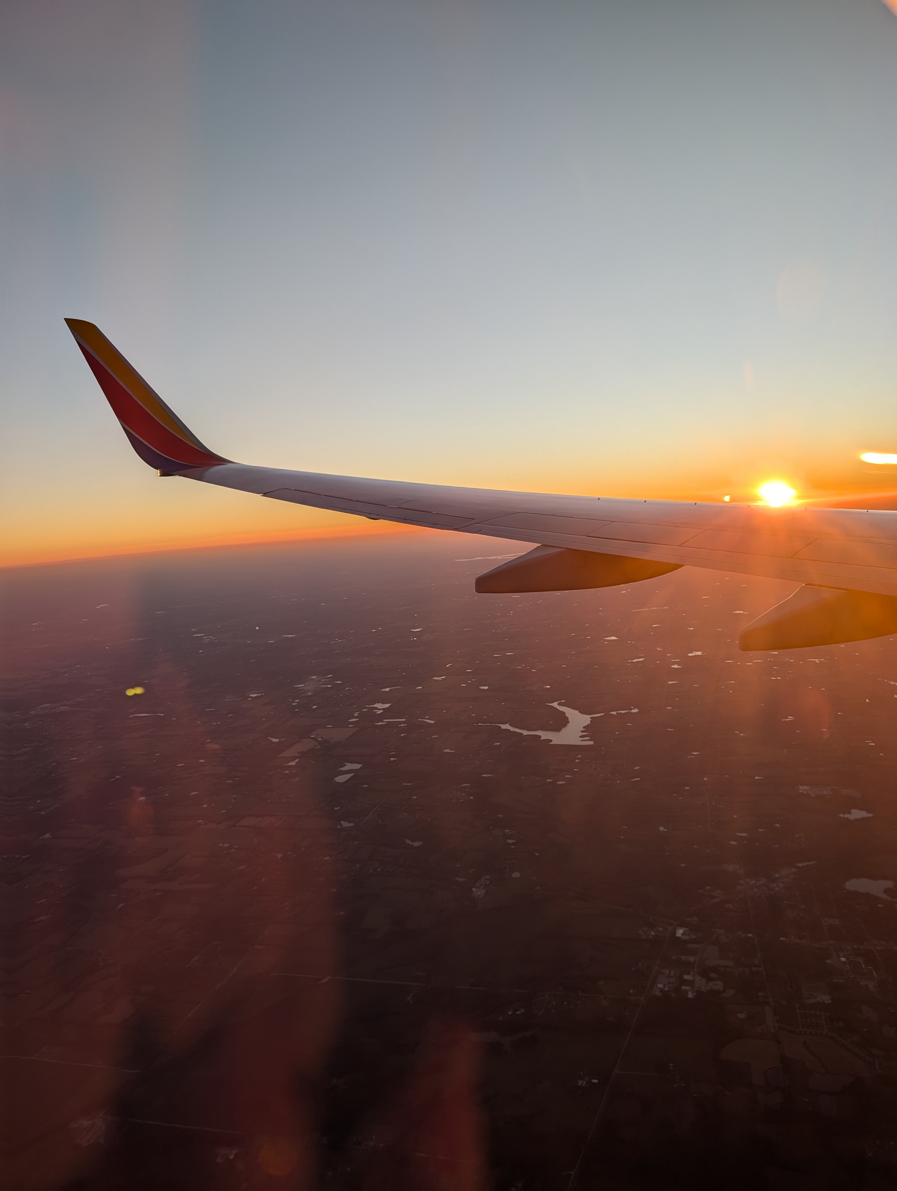 View of a plane wing and sunset on the horizon