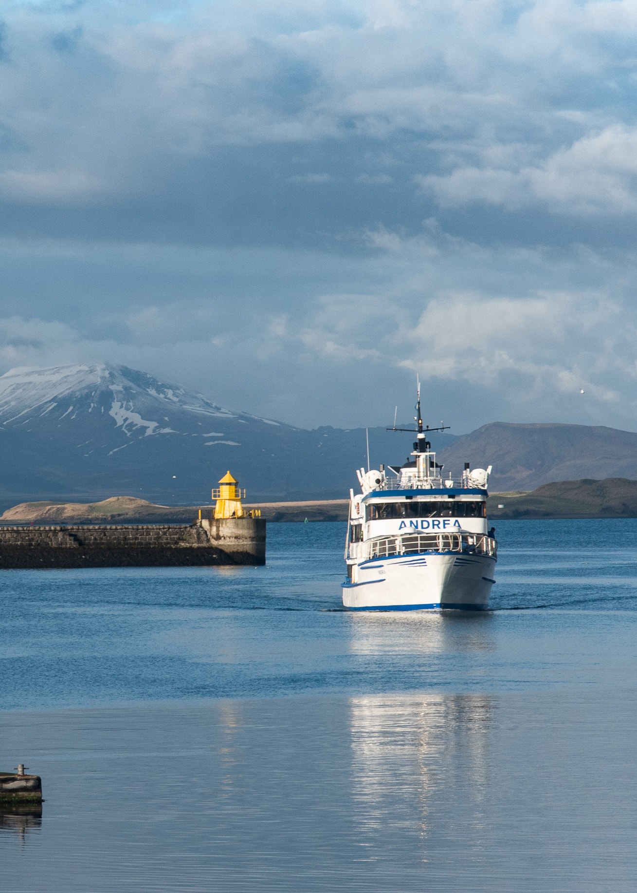 View of a ferry on a glassy sea with mountains in the distance