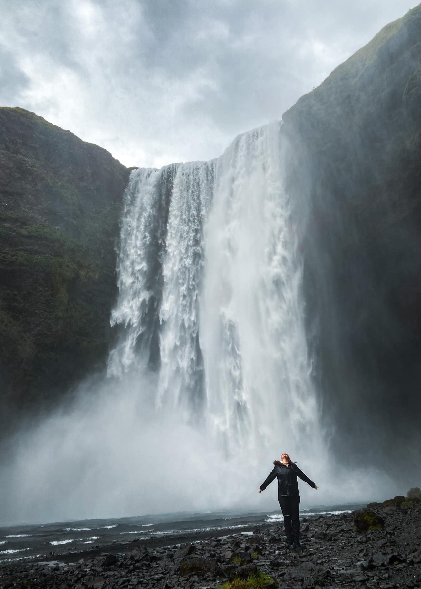 Advisor standing before a large waterfall on a cloudy day