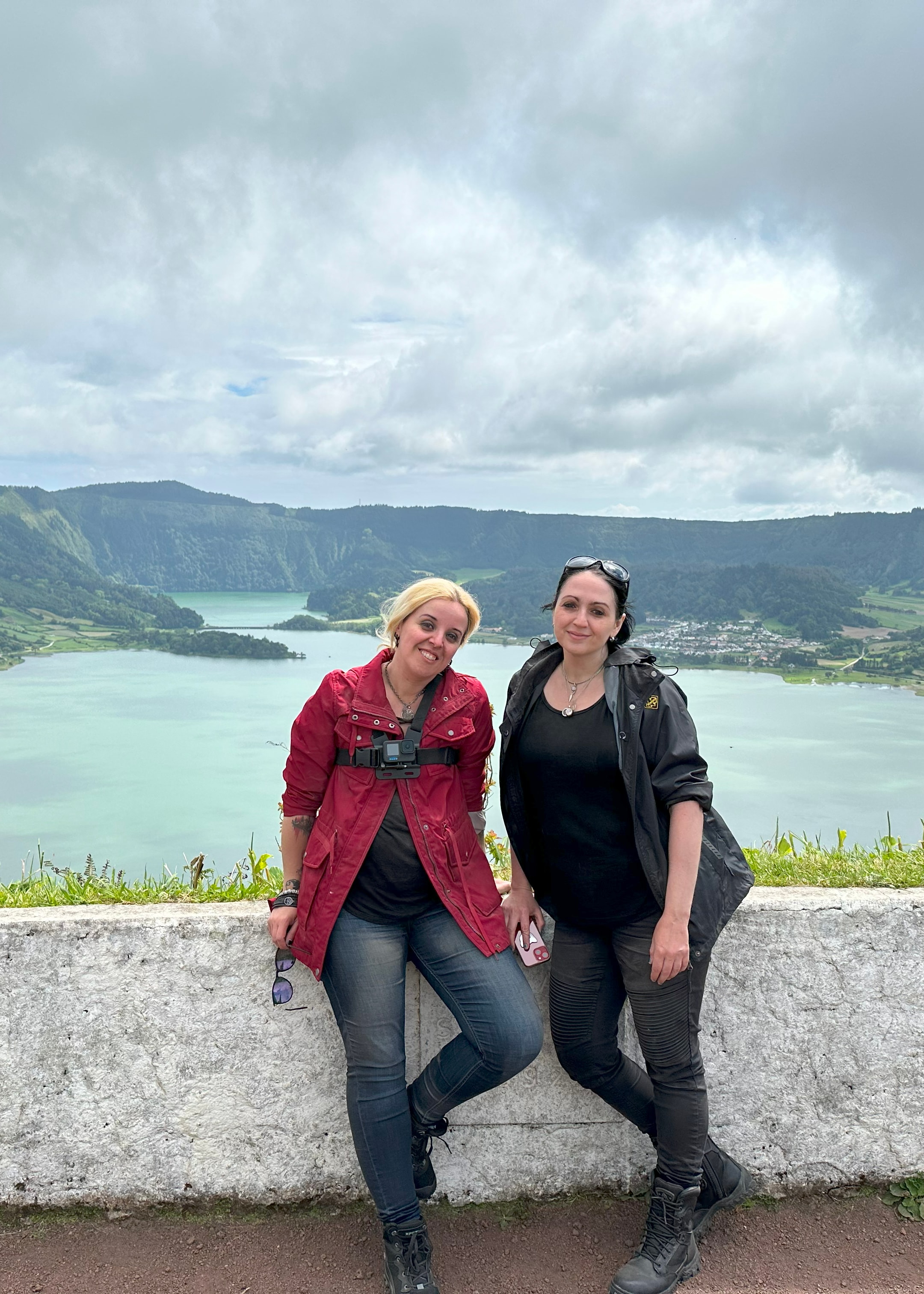 Advisor and her mother sitting side by side on a stone ledge overlooking the sea and distant mountains