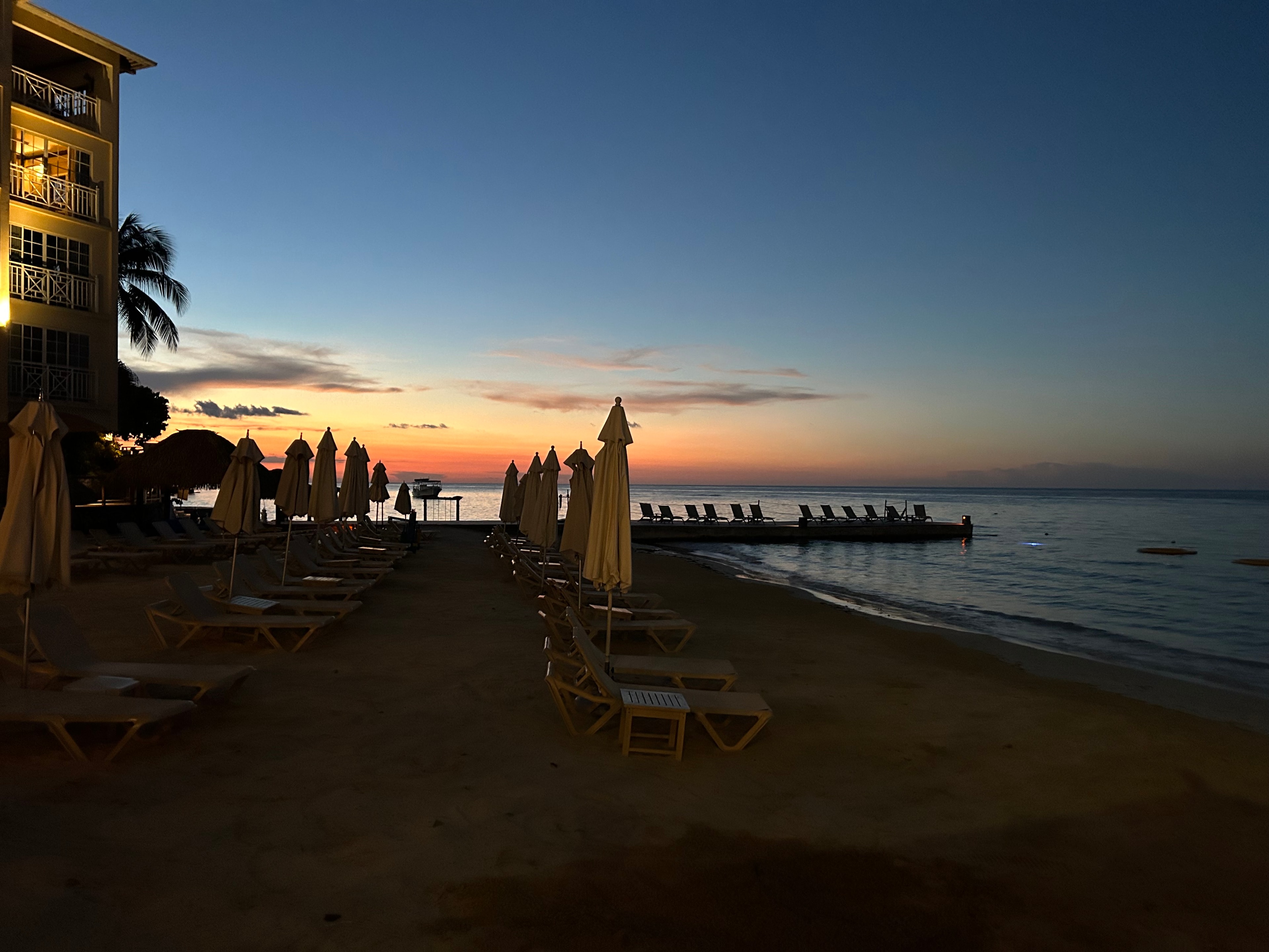 Last light of an orange sunset over the sea as seen from a resort beach