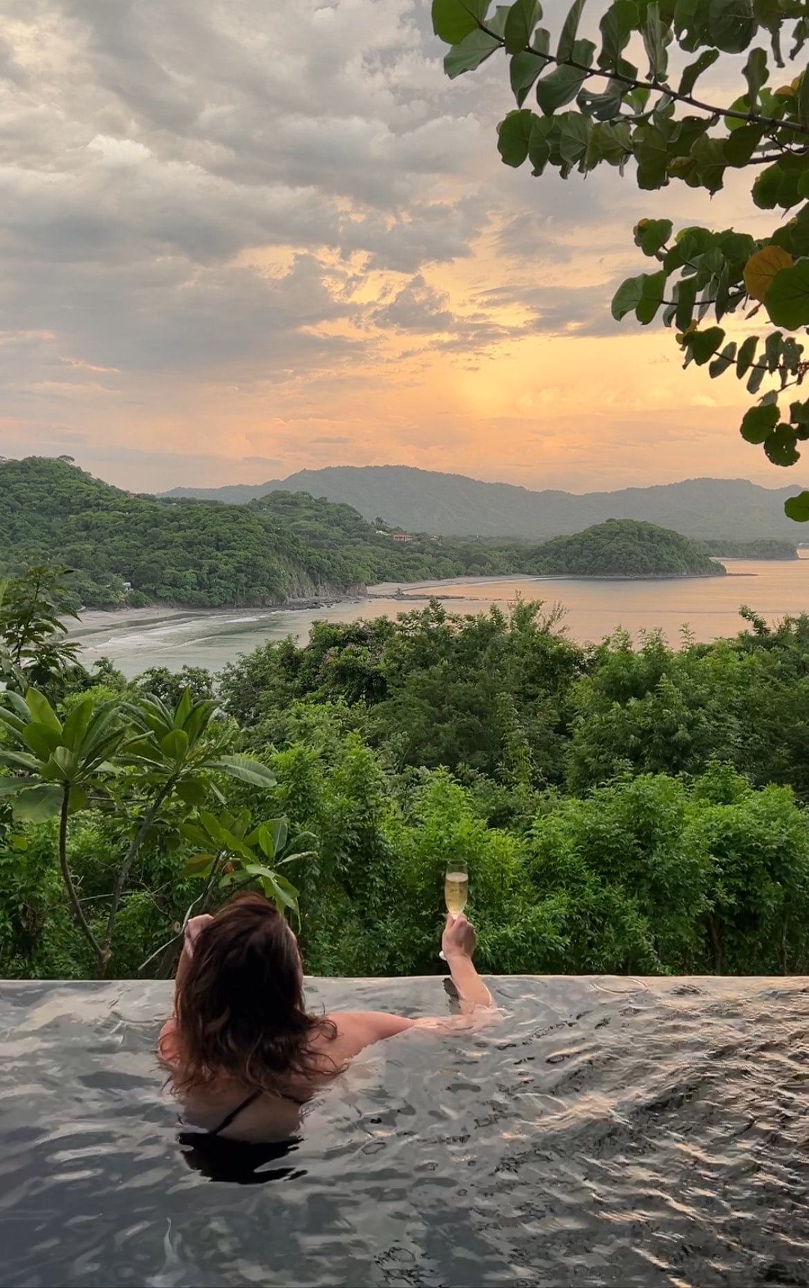 Advisor in an infinity pool overlooking the jungle and the sea at sunset