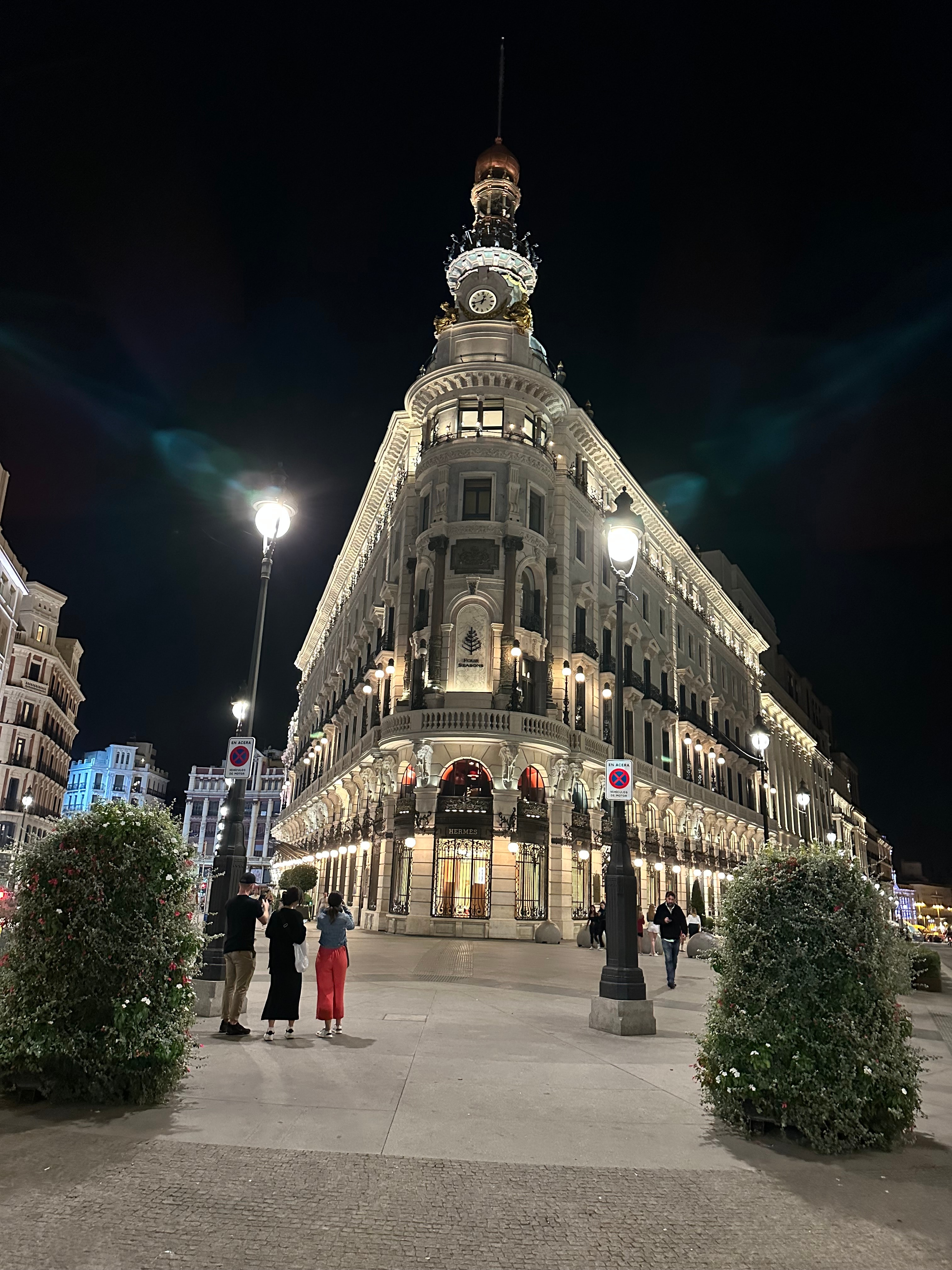 View of a triangular shaped city building lit up against a black night sky