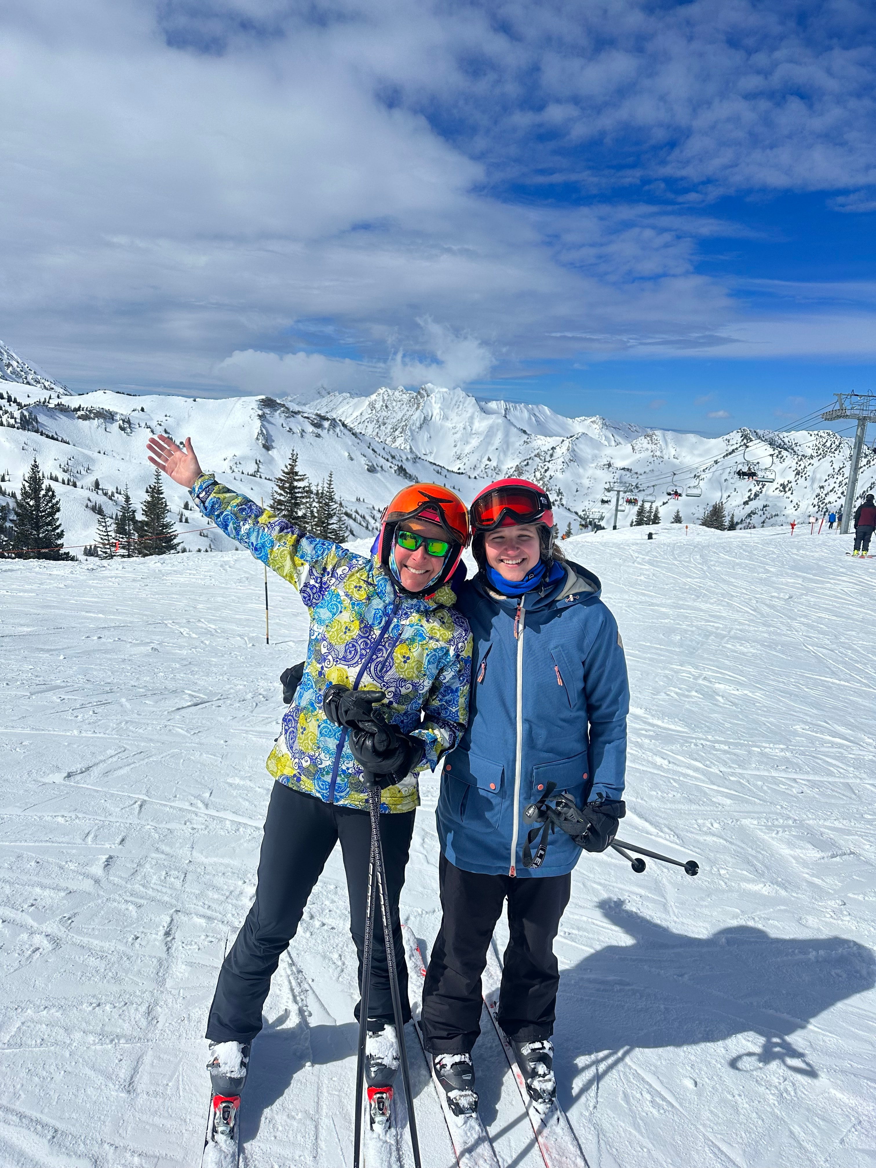 Advisor and child posing side by side wearing skis on the side of the mountain