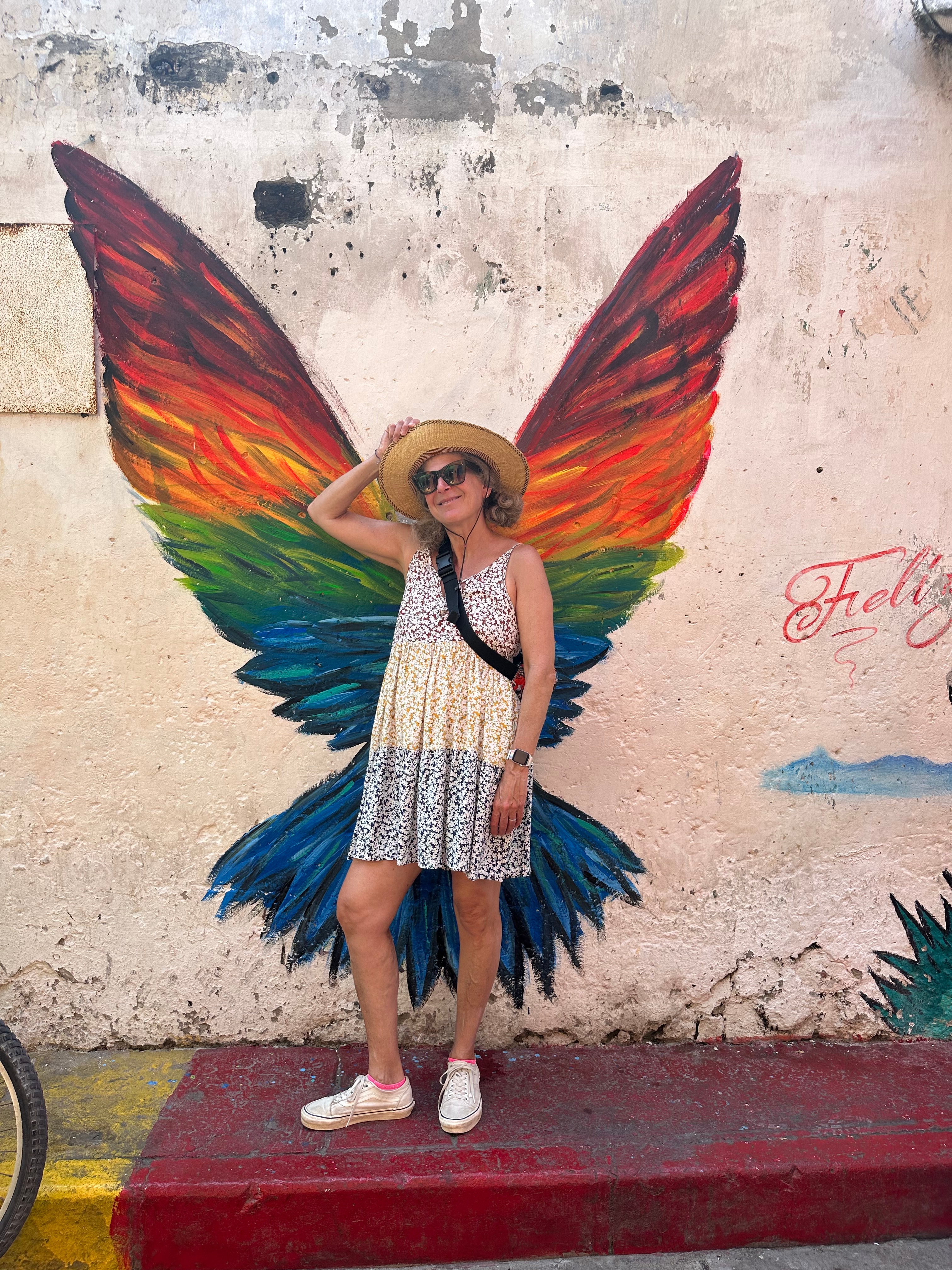 Advisor posing against a white wall with a colorful painting of wings behind her