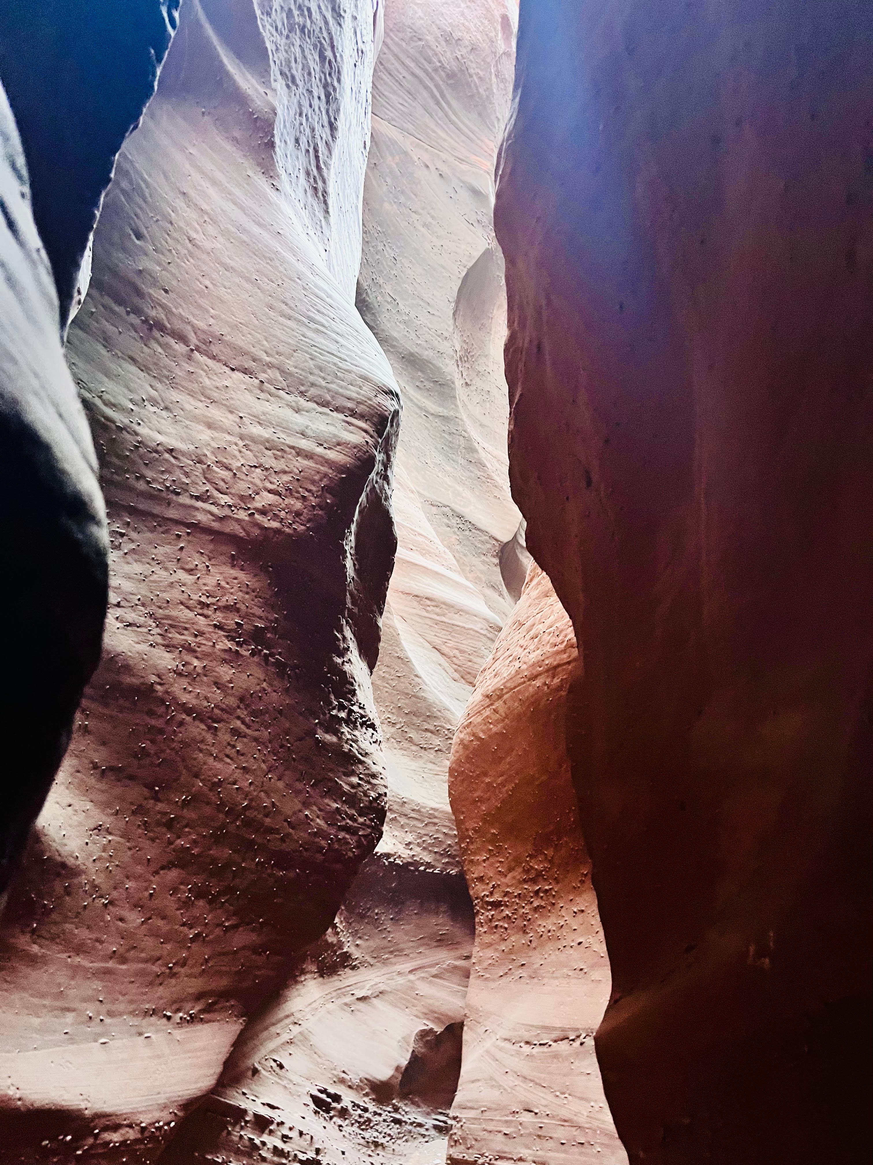 View of a narrow canyon with sunlight shining between red rocks