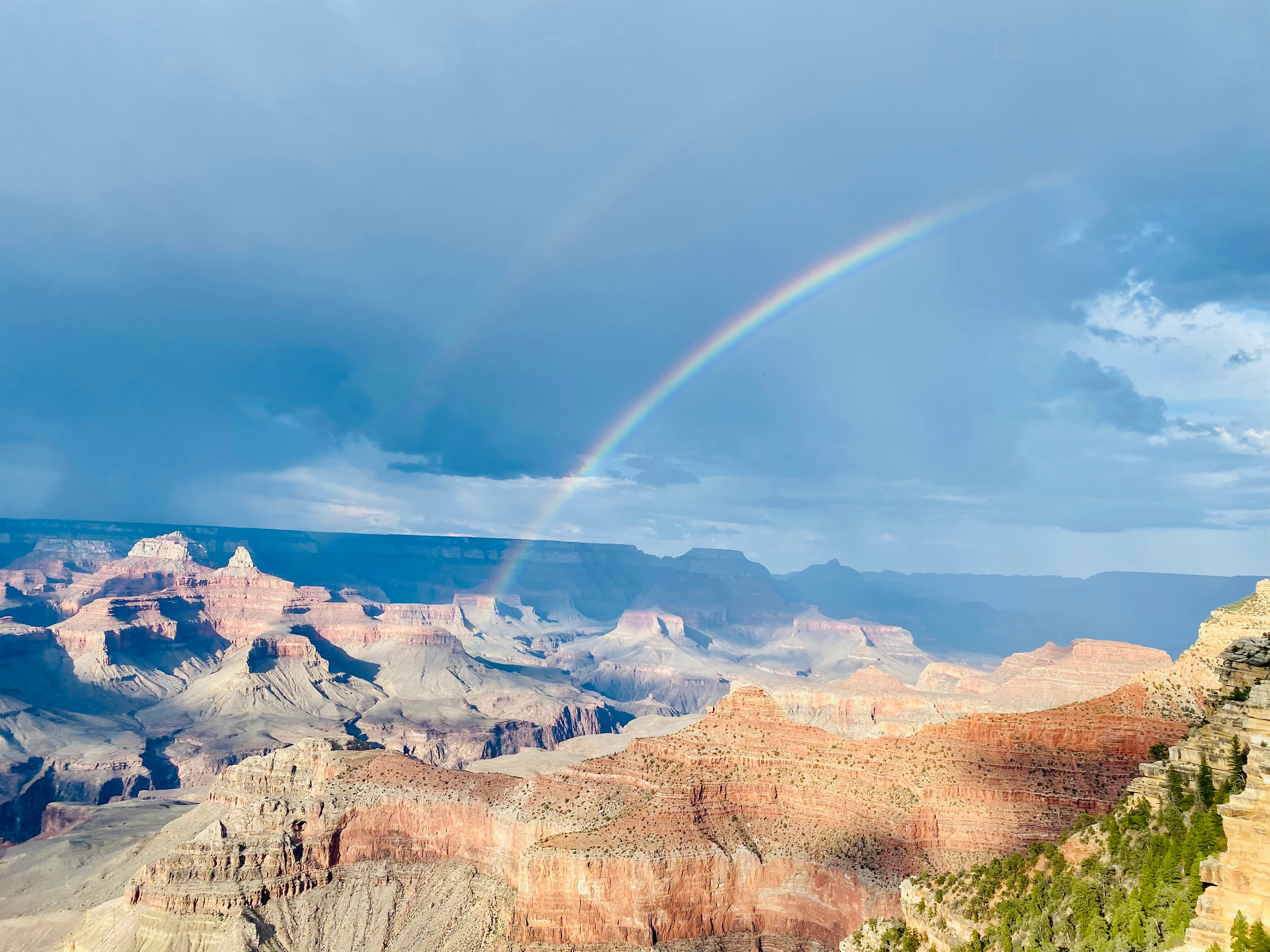 View of the canyons with a rainbow overhead during the daytime.