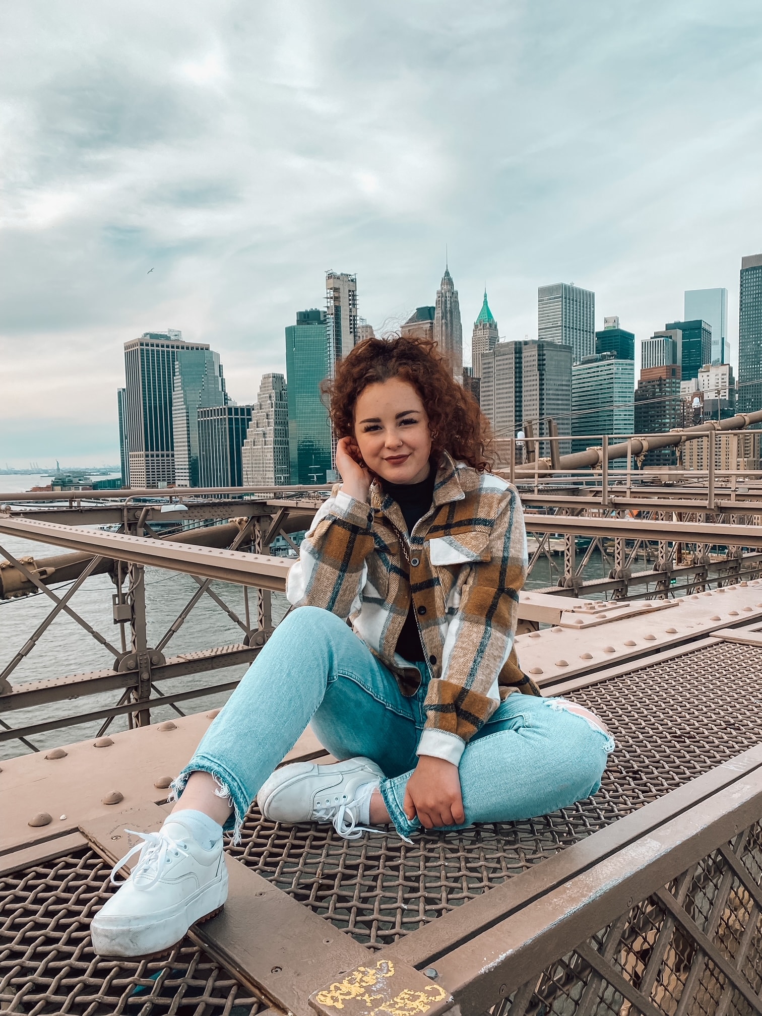 Advisor sitting on the side of a bridge overlooking the Manhattan skyline on a cloudy day