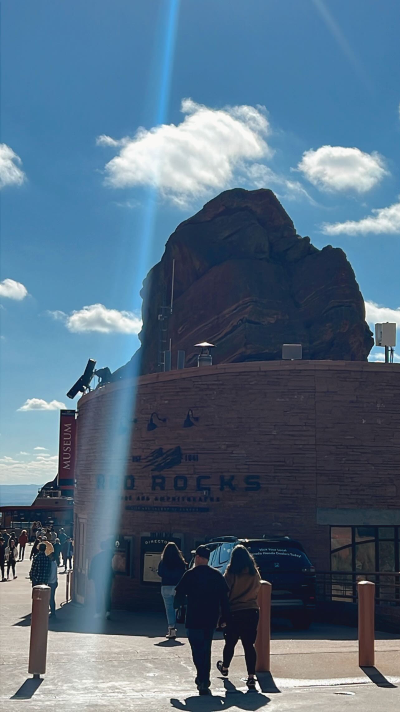 View of people standing before a large rock on a sunny day