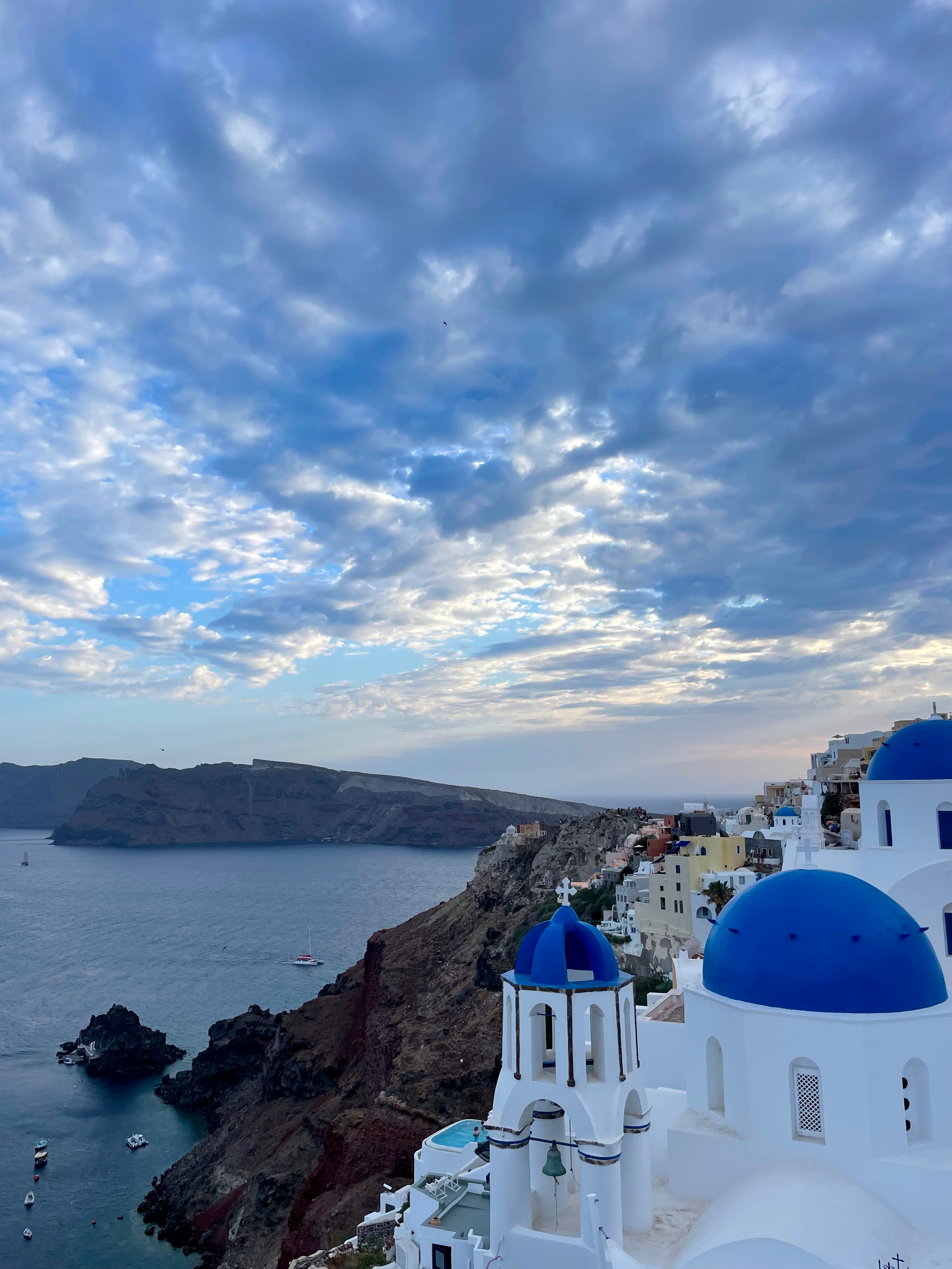 View of white buildings with blue rooftops on the Santorini coastline at dusk