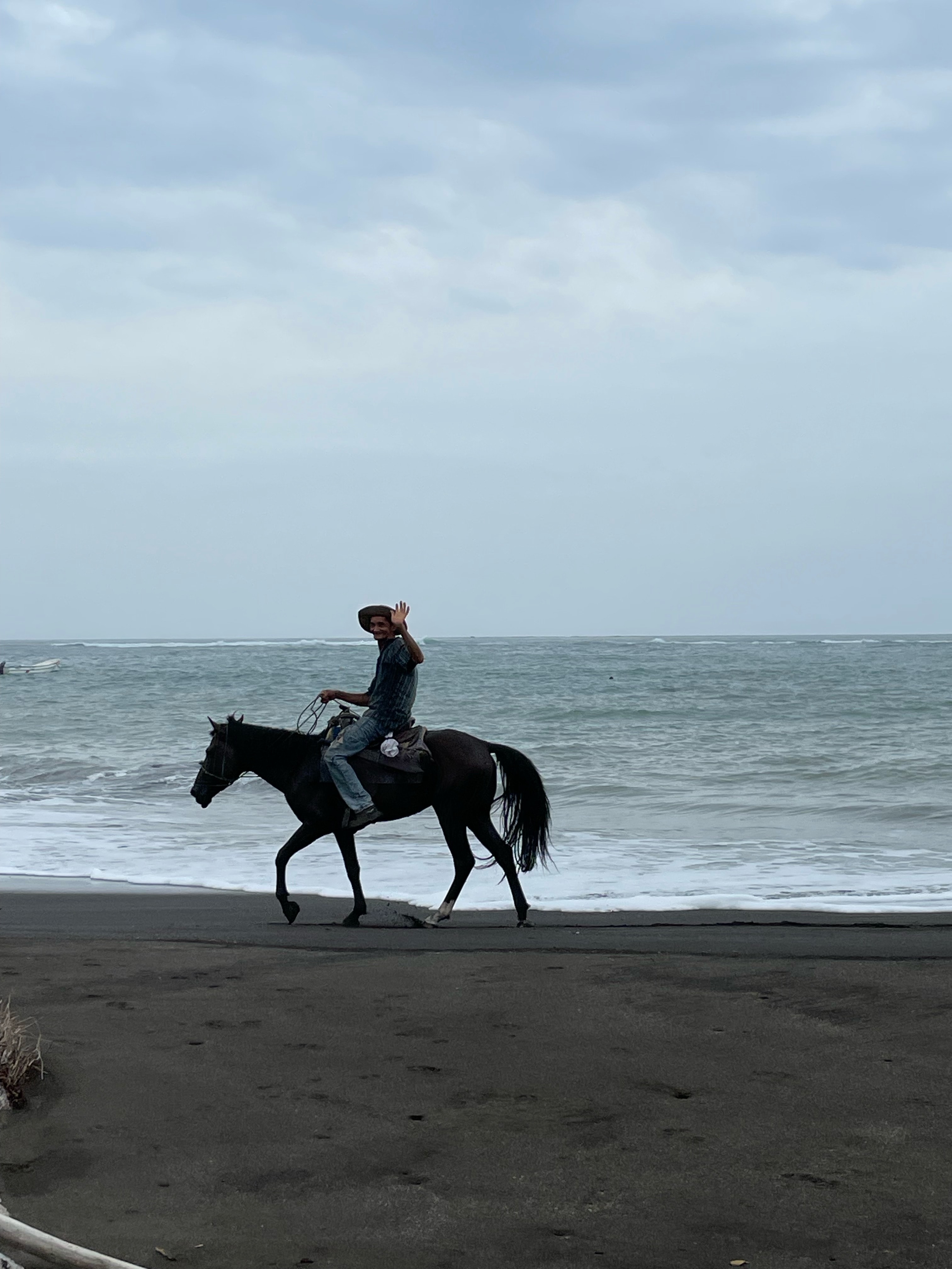 A person on horseback on the beach under cloudy skies