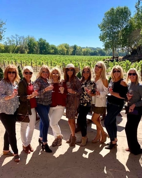 Women posing on a trip to a vineyard on a sunny day. 