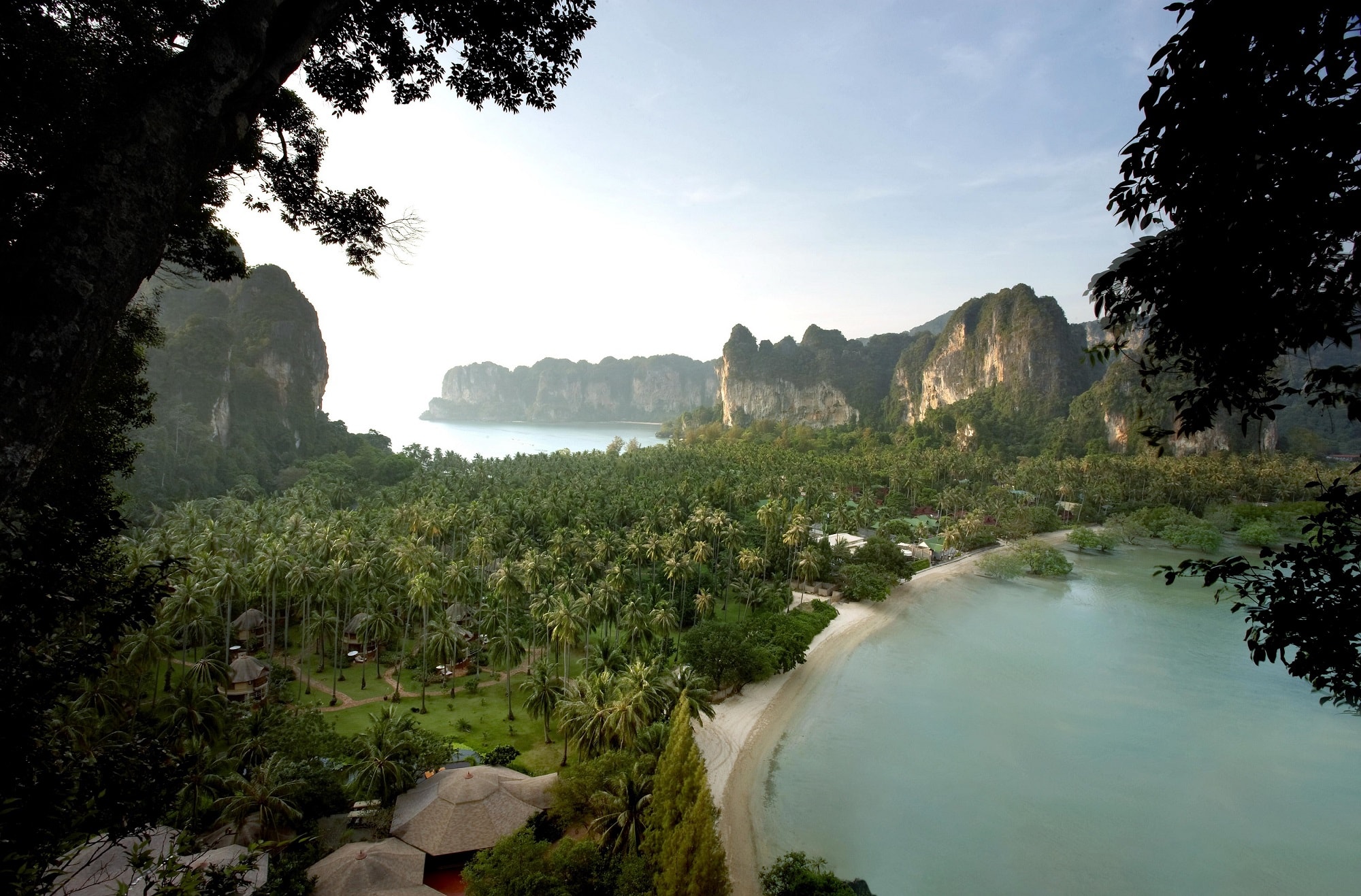 aerial view of a lush beach surrounded by the sea on one side, and a lagoon on the other