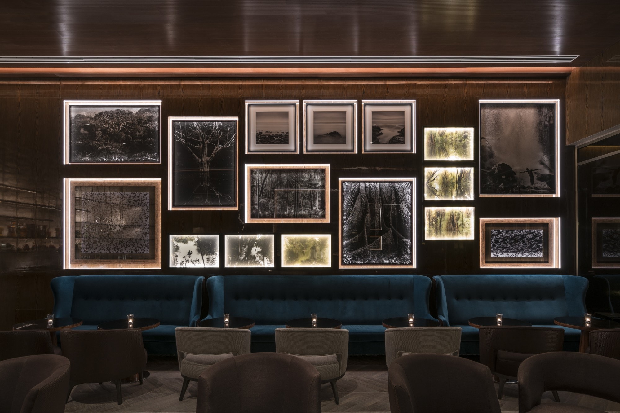 blue seats and wooden tables in front of a wall filled with pictures