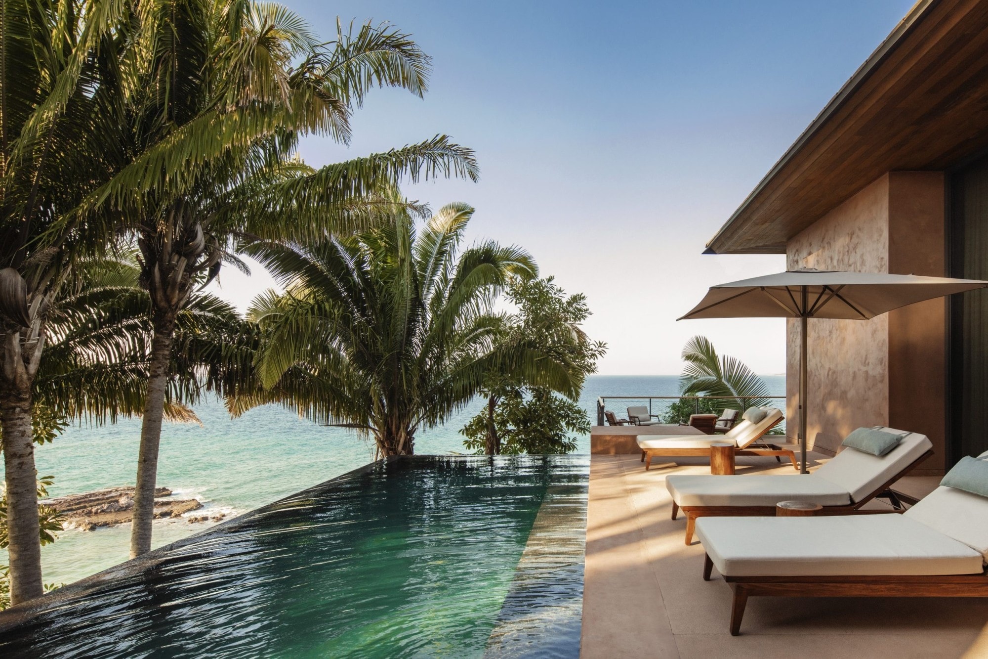 white lounge chairs near an infinity pool overlooking the ocean