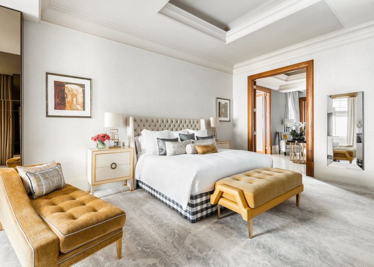 stylish hotel room with yellow benches and a bed with a checkered underskirt