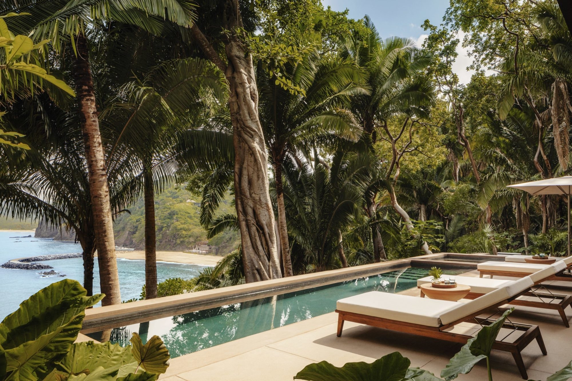 plush loungers next to a sleek terrace plunge pool overlook the jungle and ocean