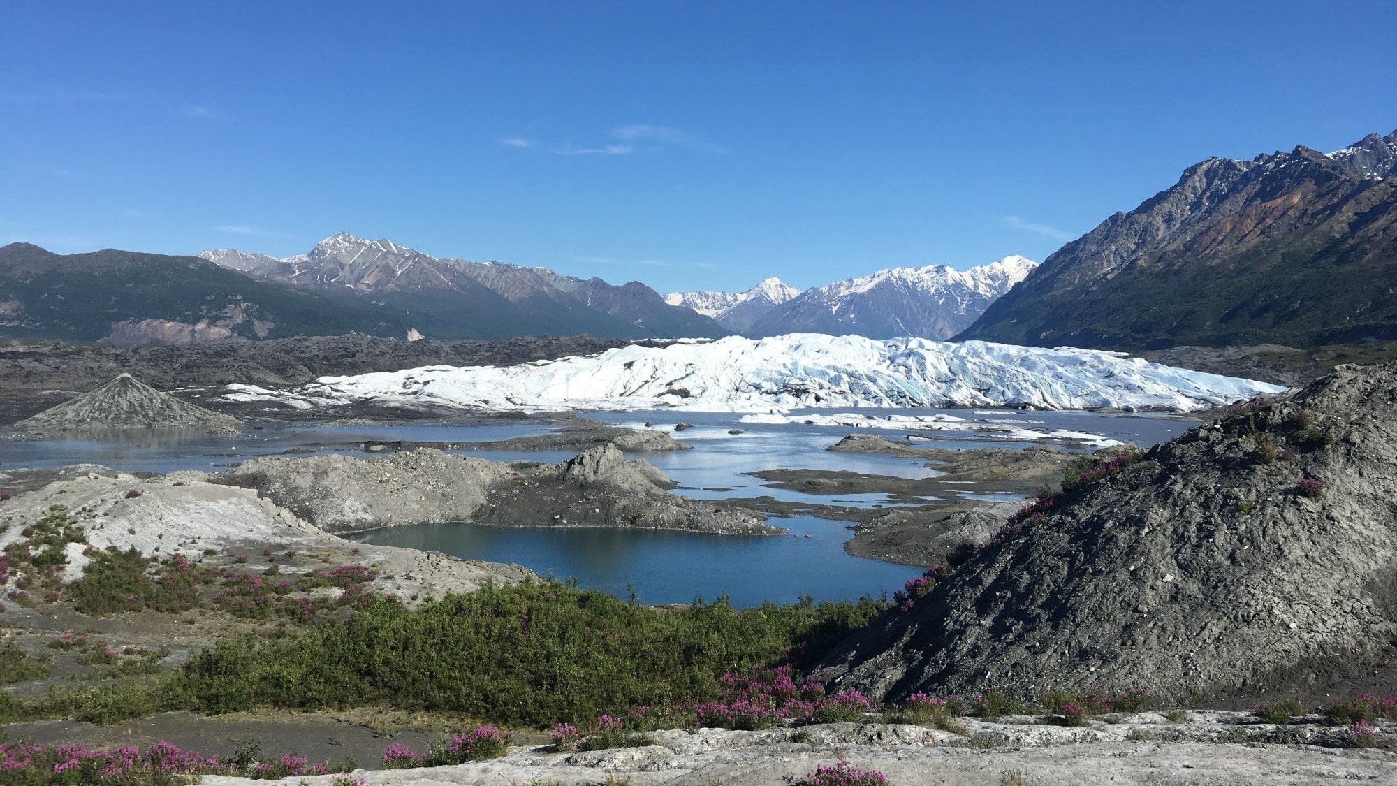 A glacier during day time surrounded by mountains.