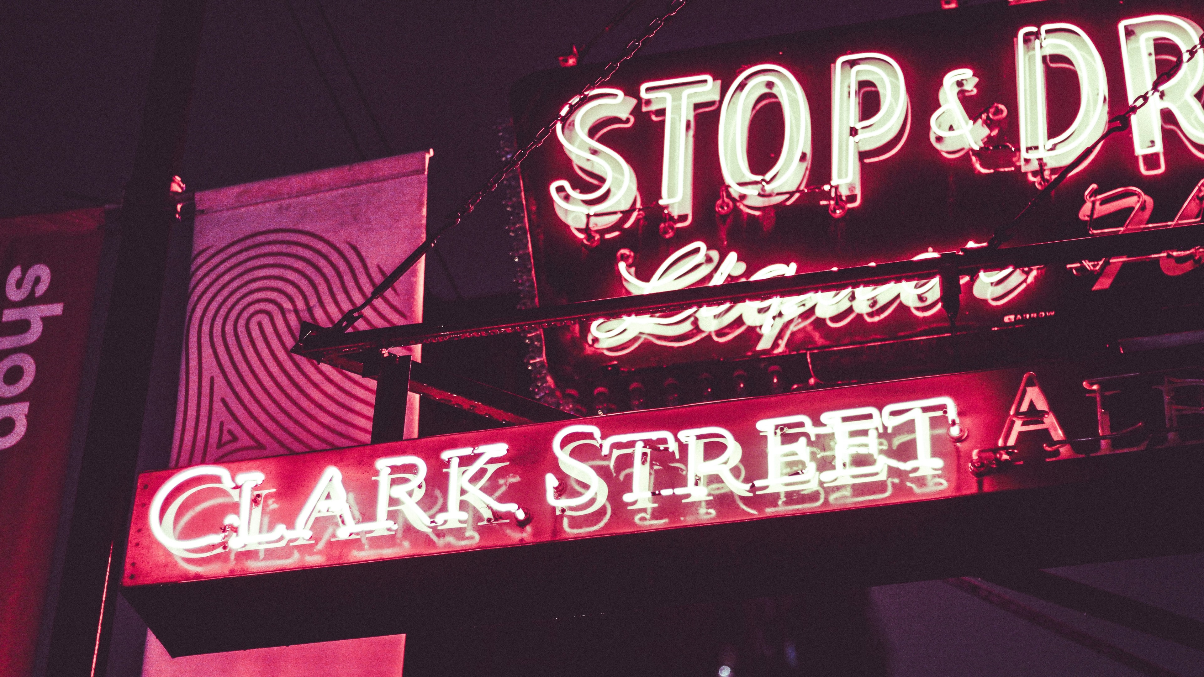 A red neon sign marking the entrance to a bar.