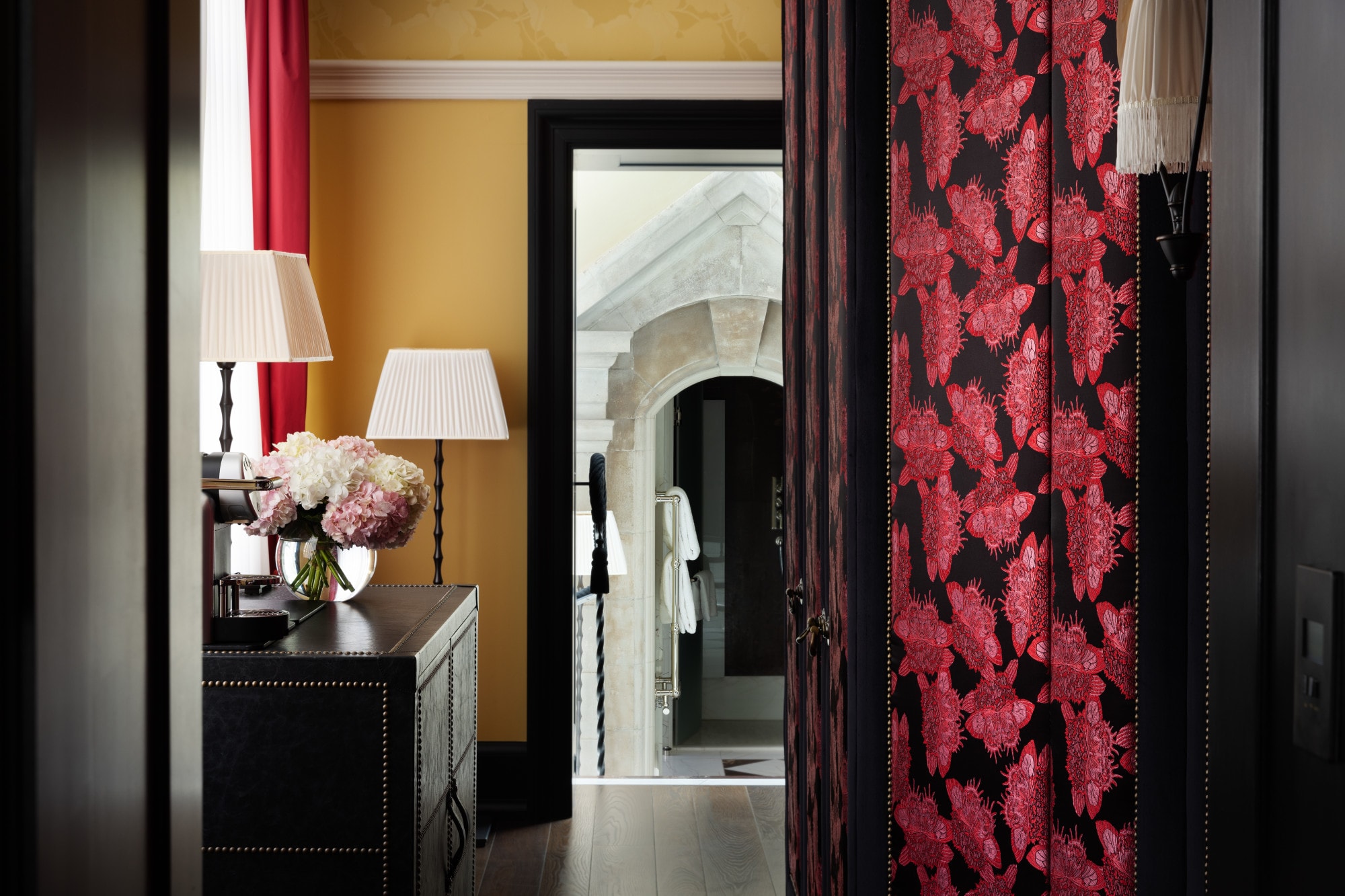 a fancy hallway in a hotel room with red-flower wall paper and wooden floors