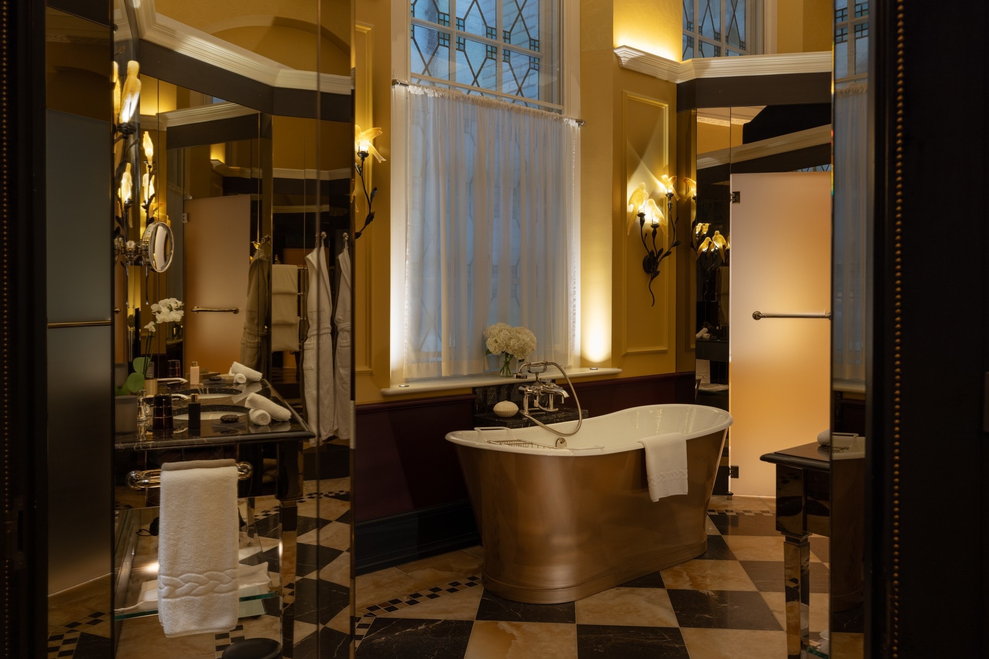 a copper bathtub in a fancy dimly lit hotel bathroom