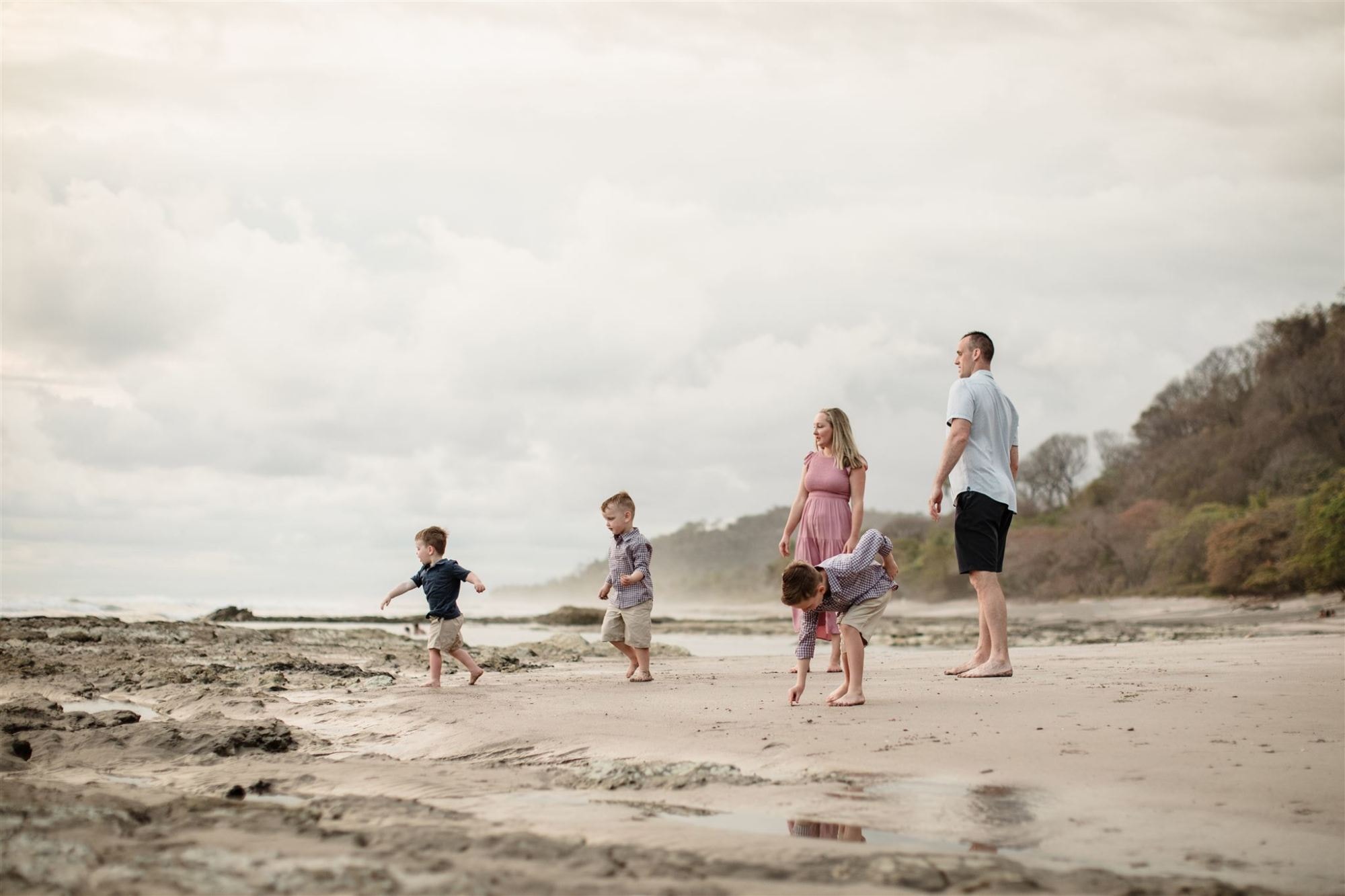 A family of five standing on a beach.