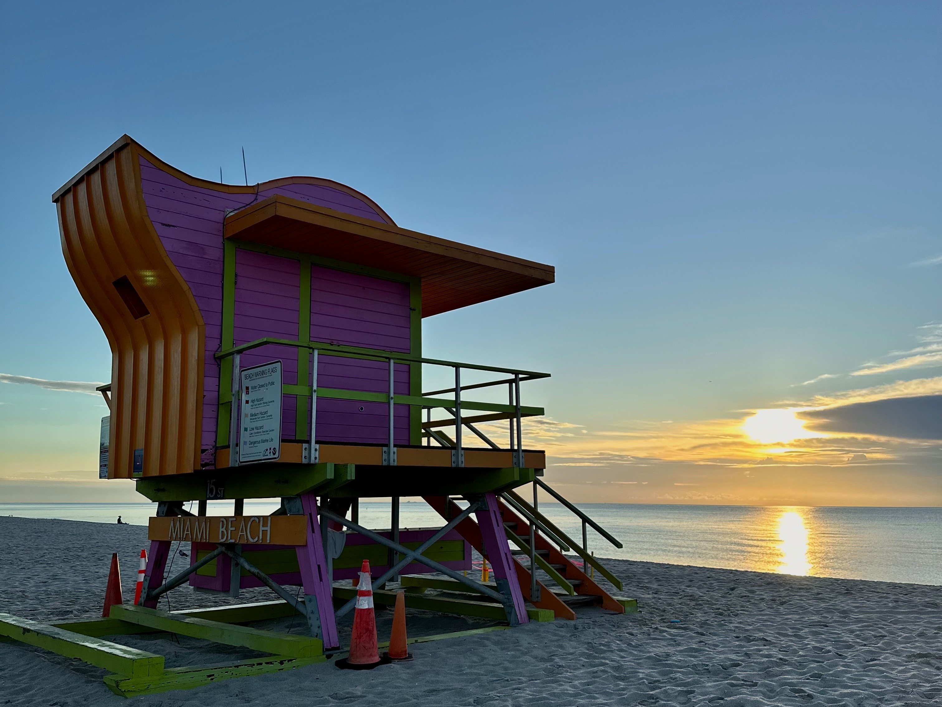 The image depicts a vibrant lifeguard tower on a beach at sunset, symbolizing safety amidst natural beauty.