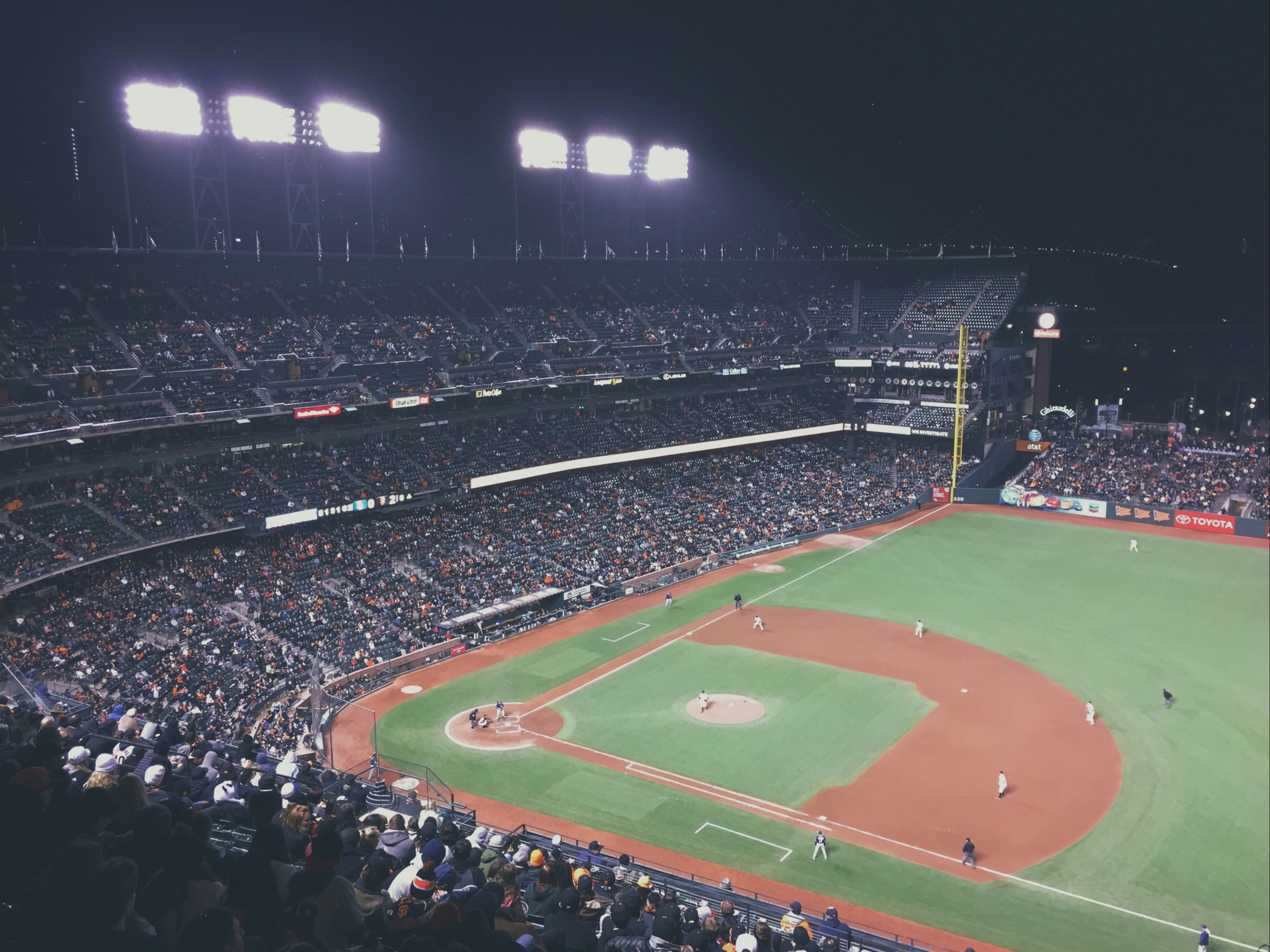 A vibrant nighttime baseball game, with a packed stadium under bright lights.