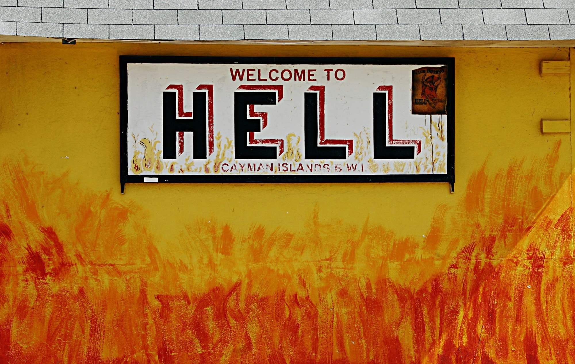 A sign saying Welcome to Hell on a yellow and orange painted wall.