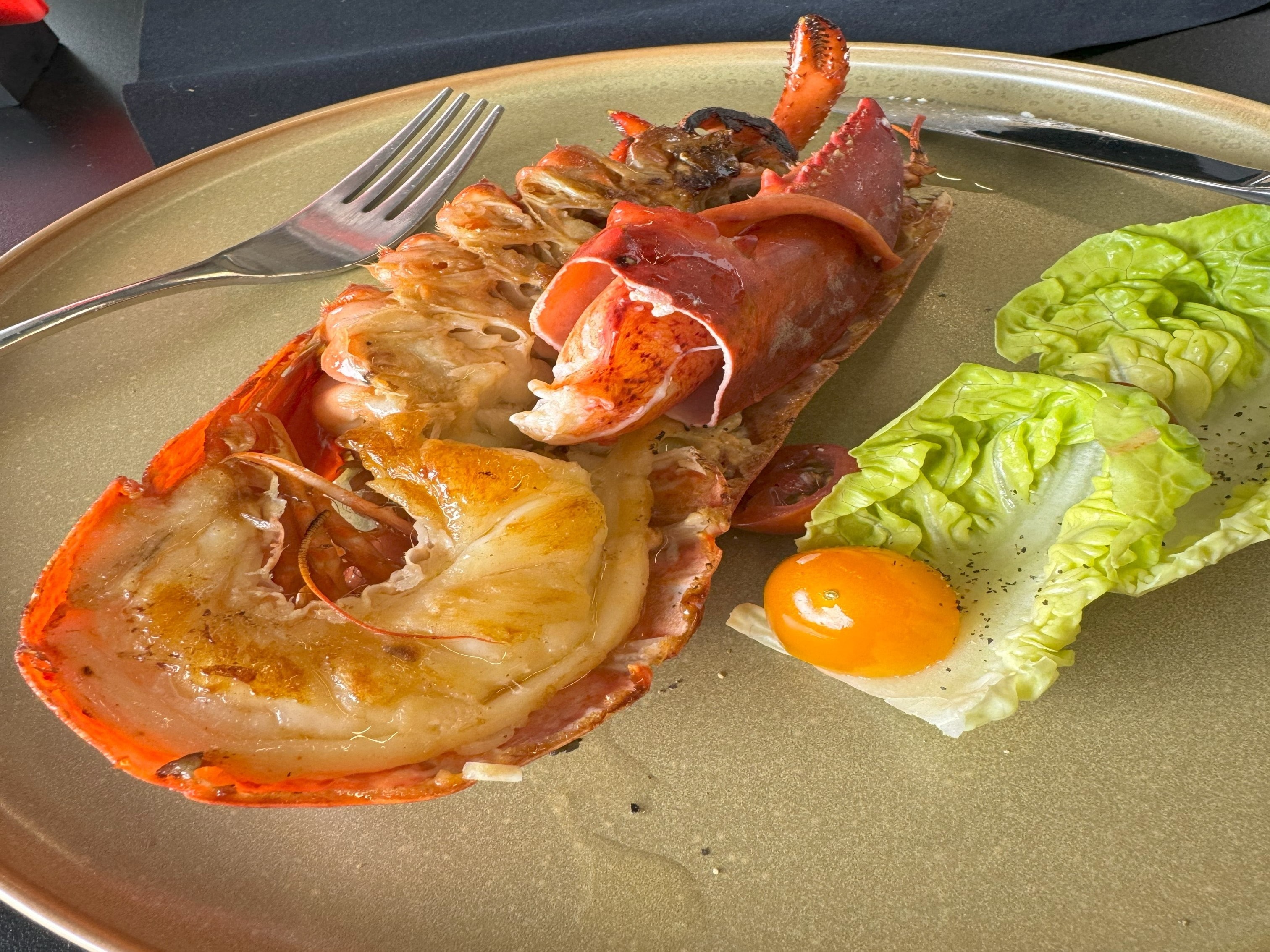 A culinary presentation of lobster tail, poised elegantly with lettuce and a golden yolk, ready to delight the senses.