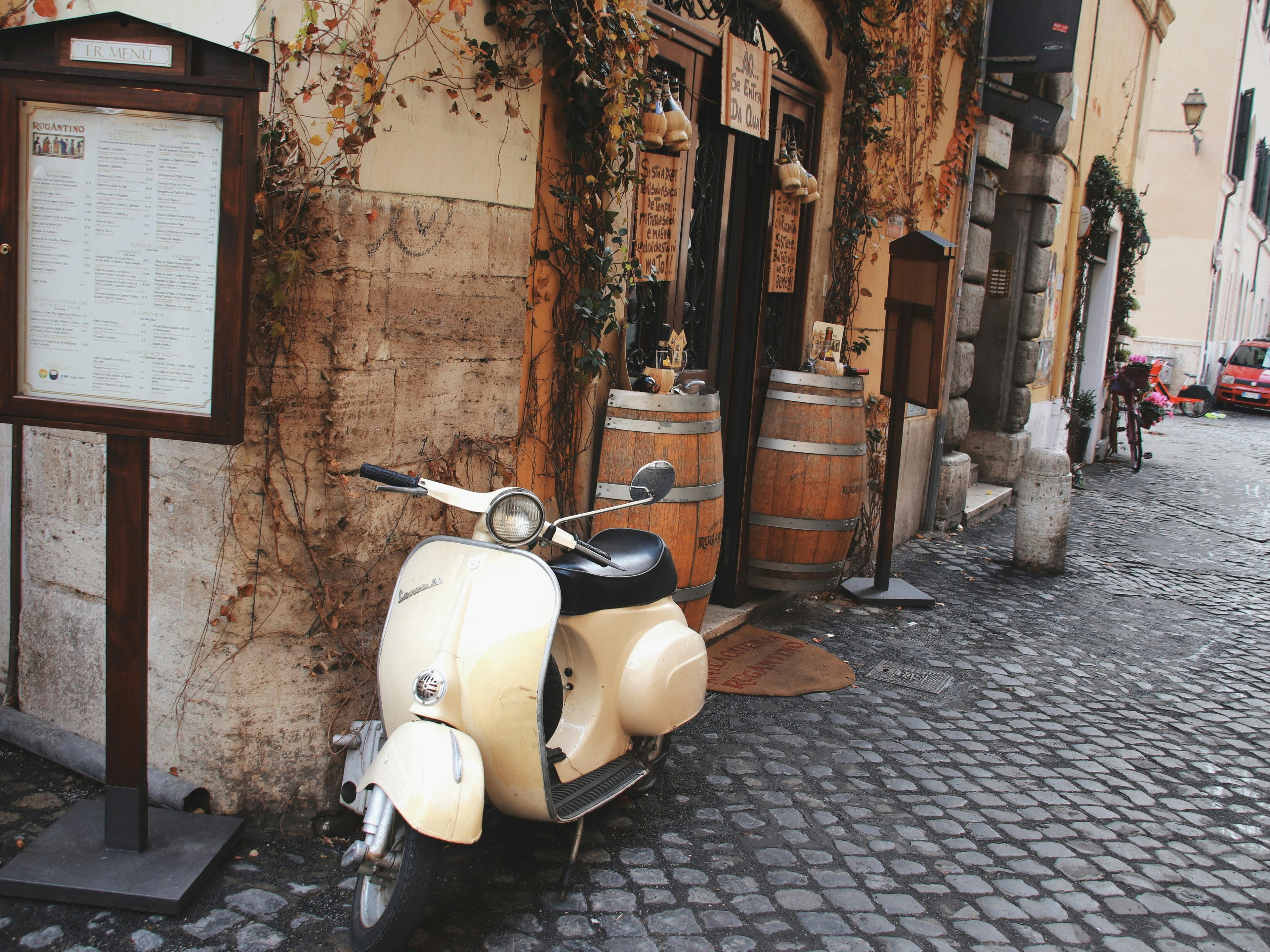 A vintage scooter resting on cobblestones next to a menu on a cobblestone street.