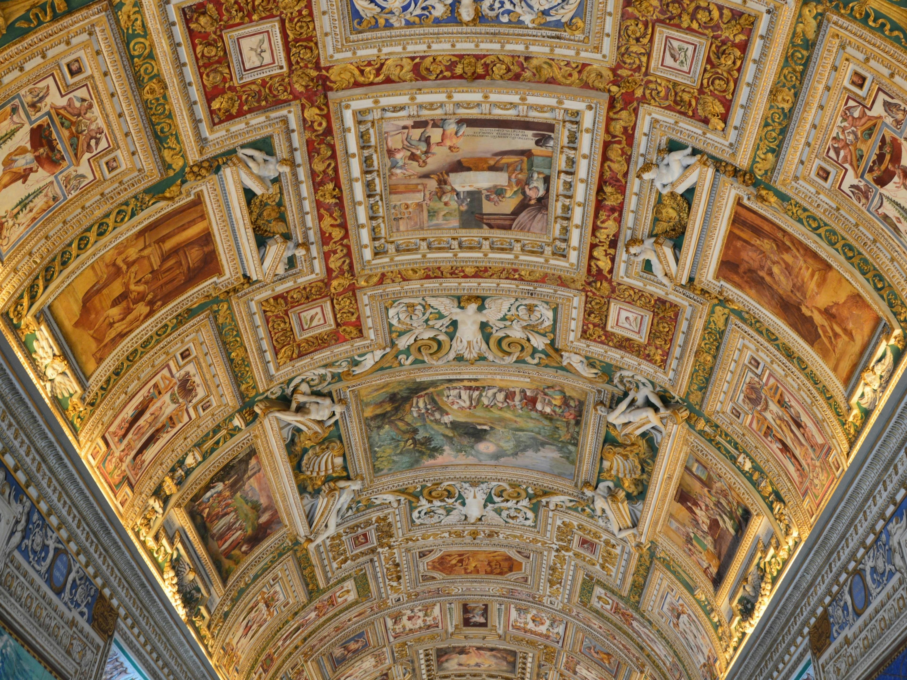 An arched ceiling decorated with framed fresco paintings.