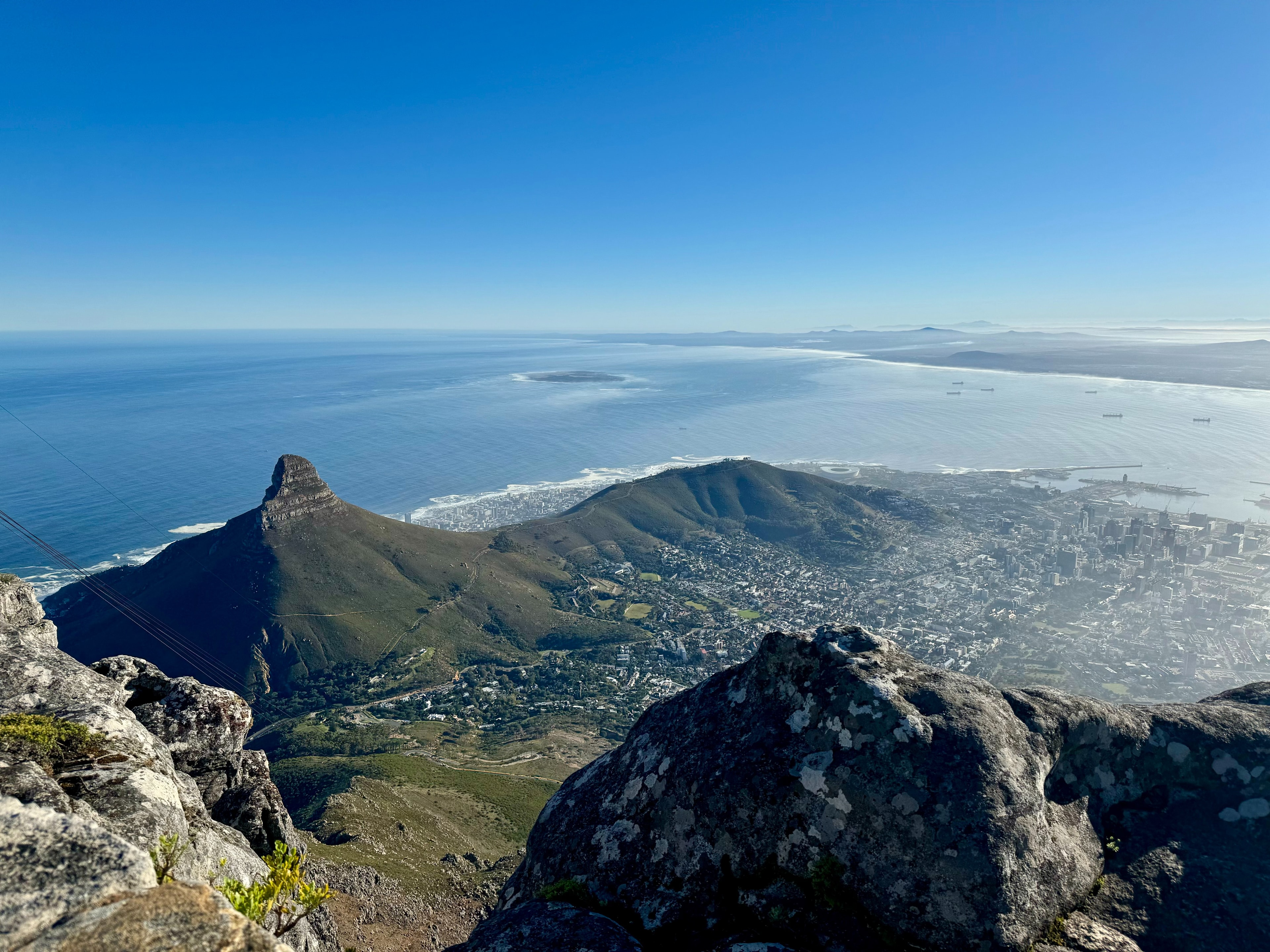 A sweeping view of a mountainous terrain and a vast water body under clear skies from a high vantage point.