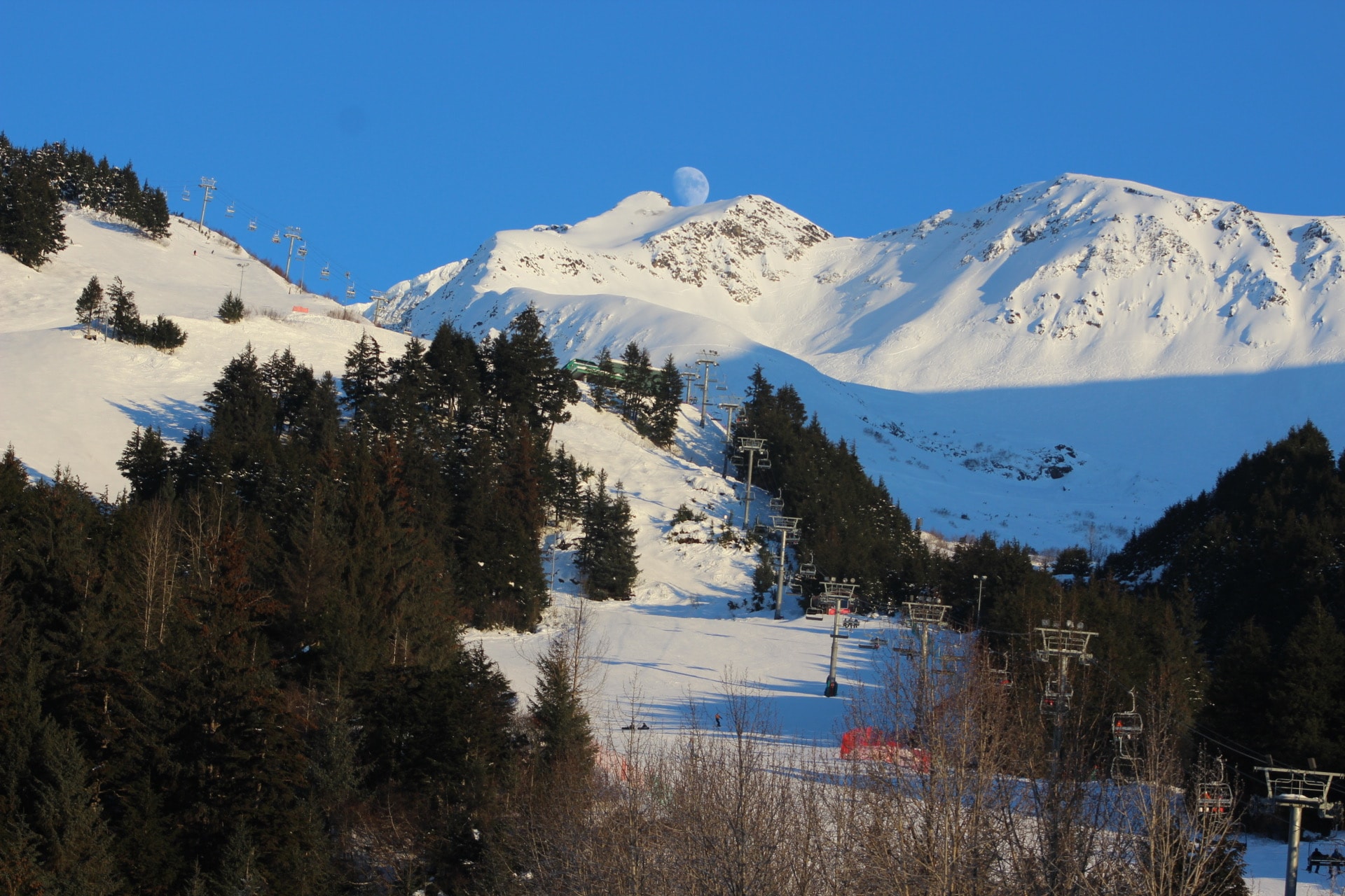 Beautiful view of snow covered mountains behind a sun-lit ski trail