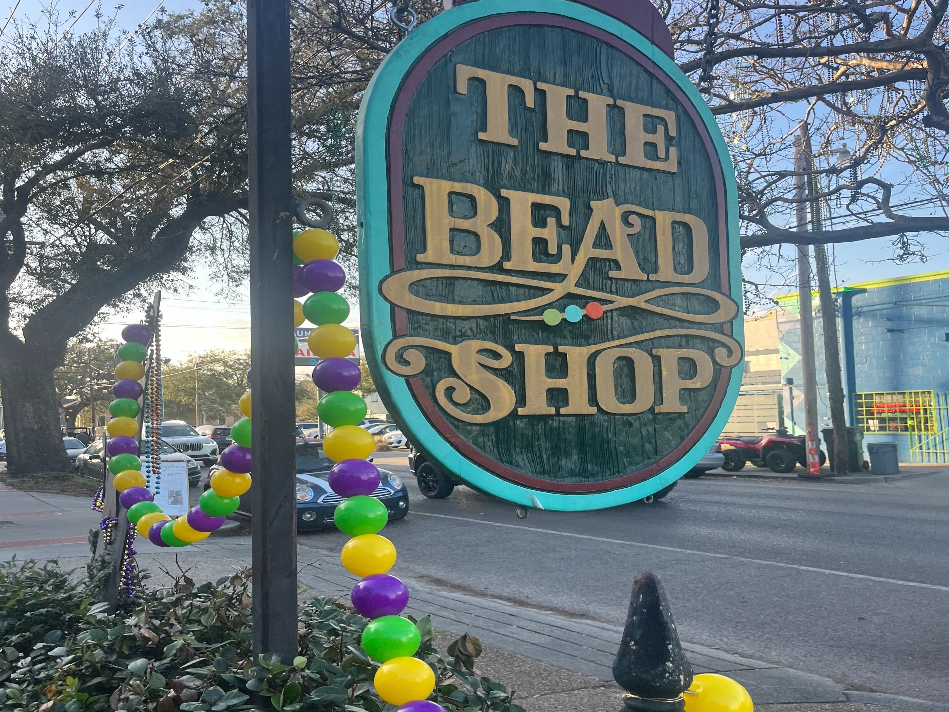 A colorful wooden sign for “The Bead Shop” with festive bead strings.