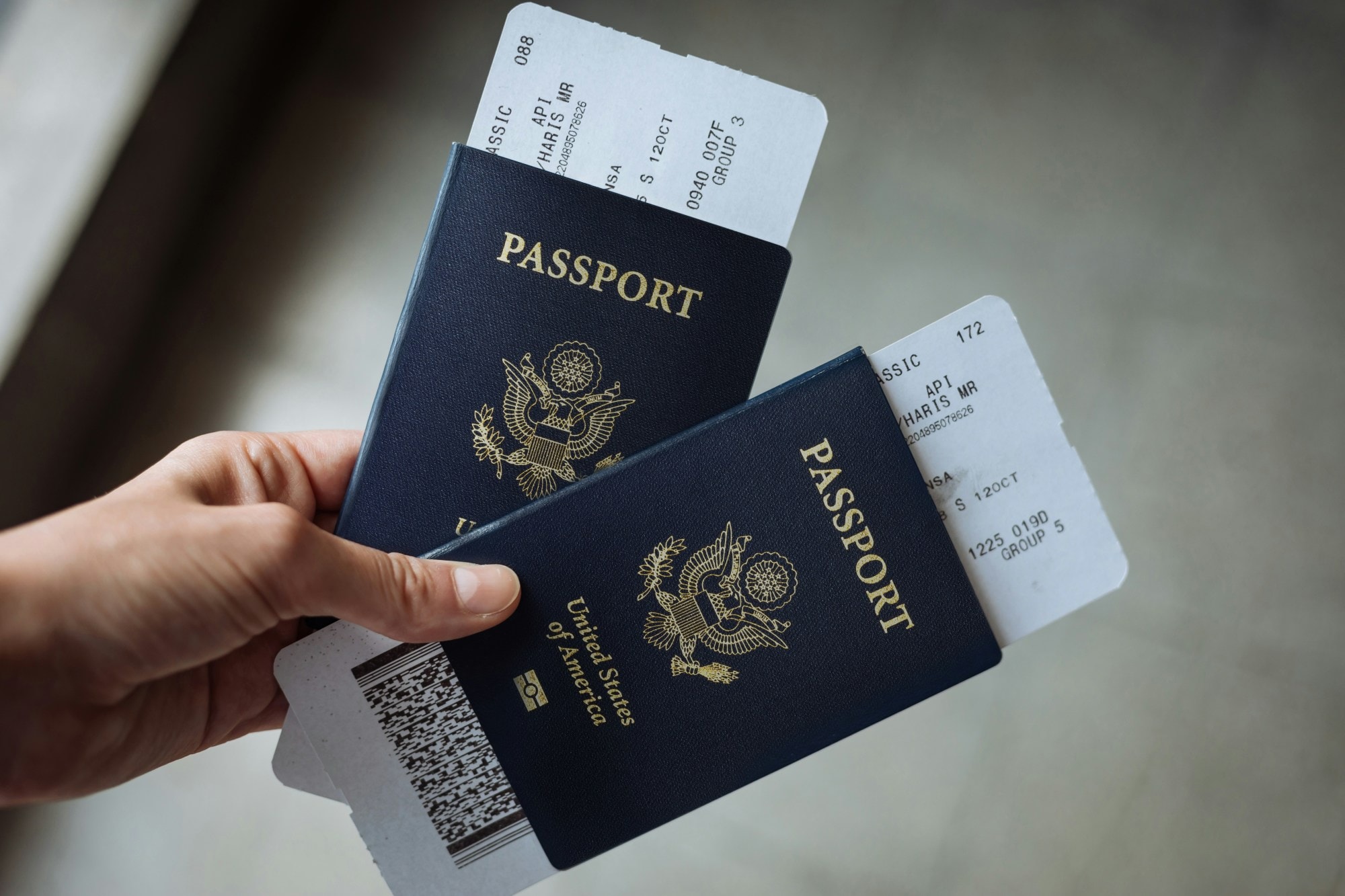 A hand holding two passports and boarding passes