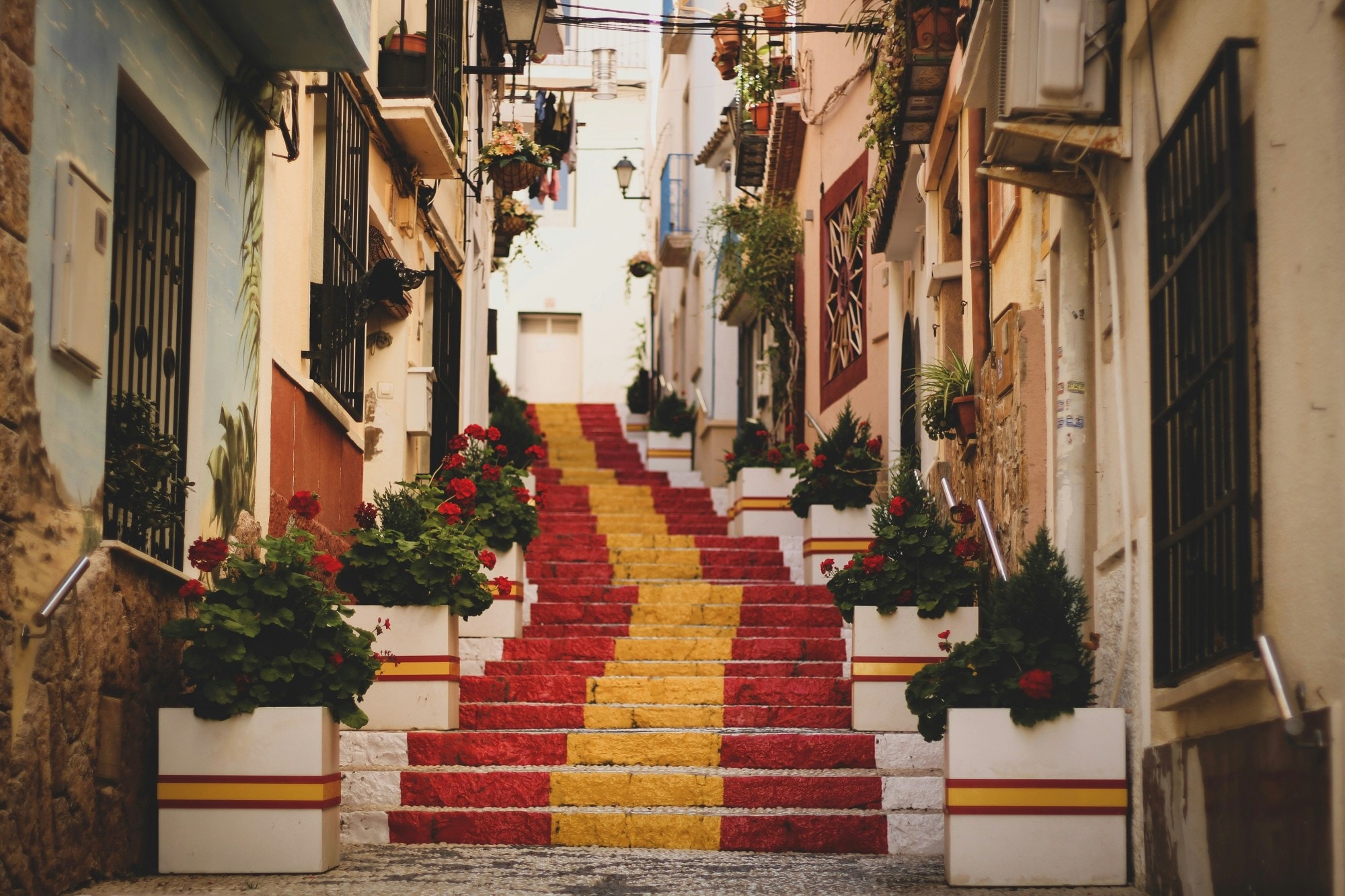 A street between buildings with a red and yellow painted staircase in the middle