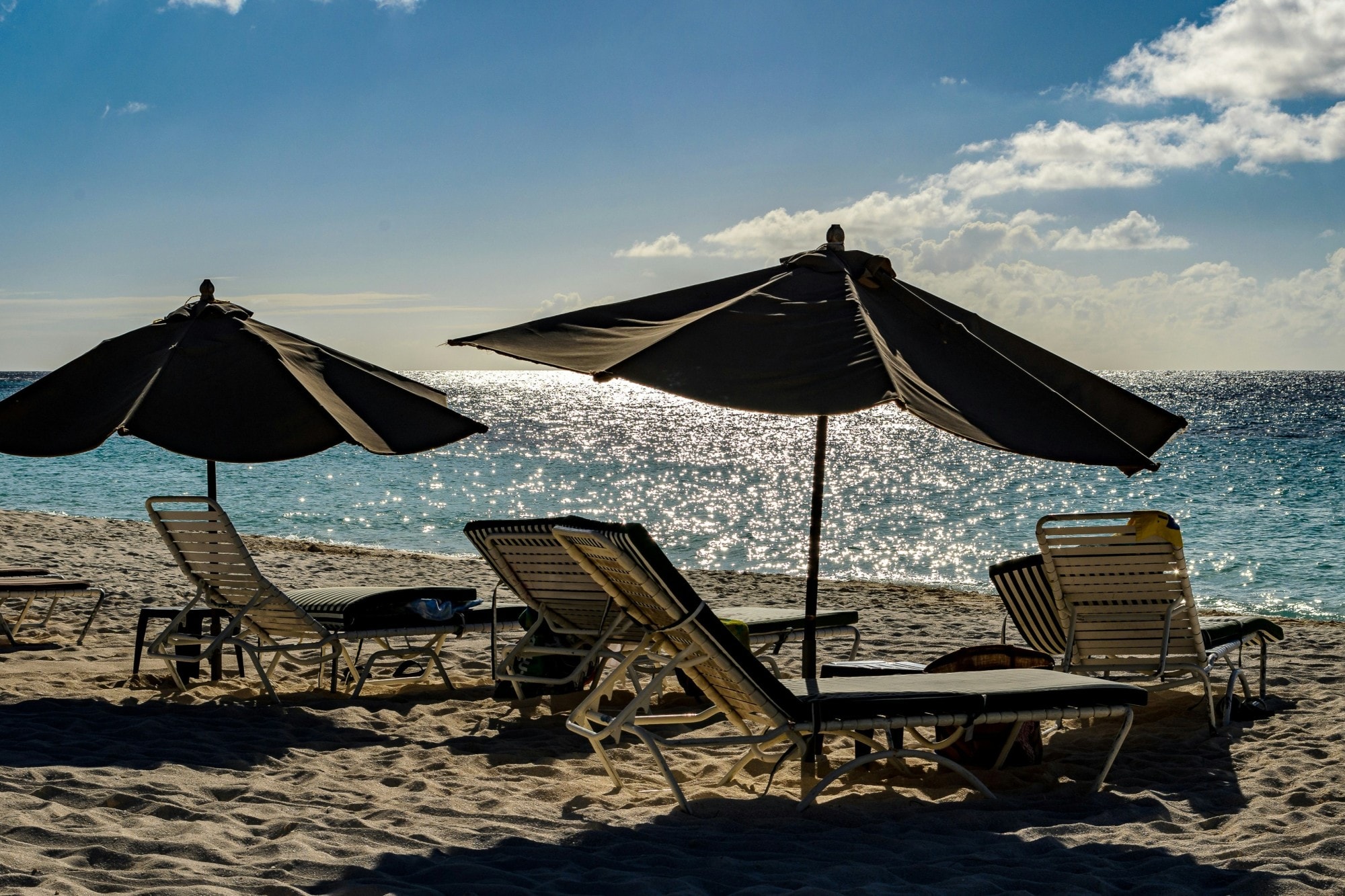 lounge chairs and beach umbrellas on sand with view of the sea