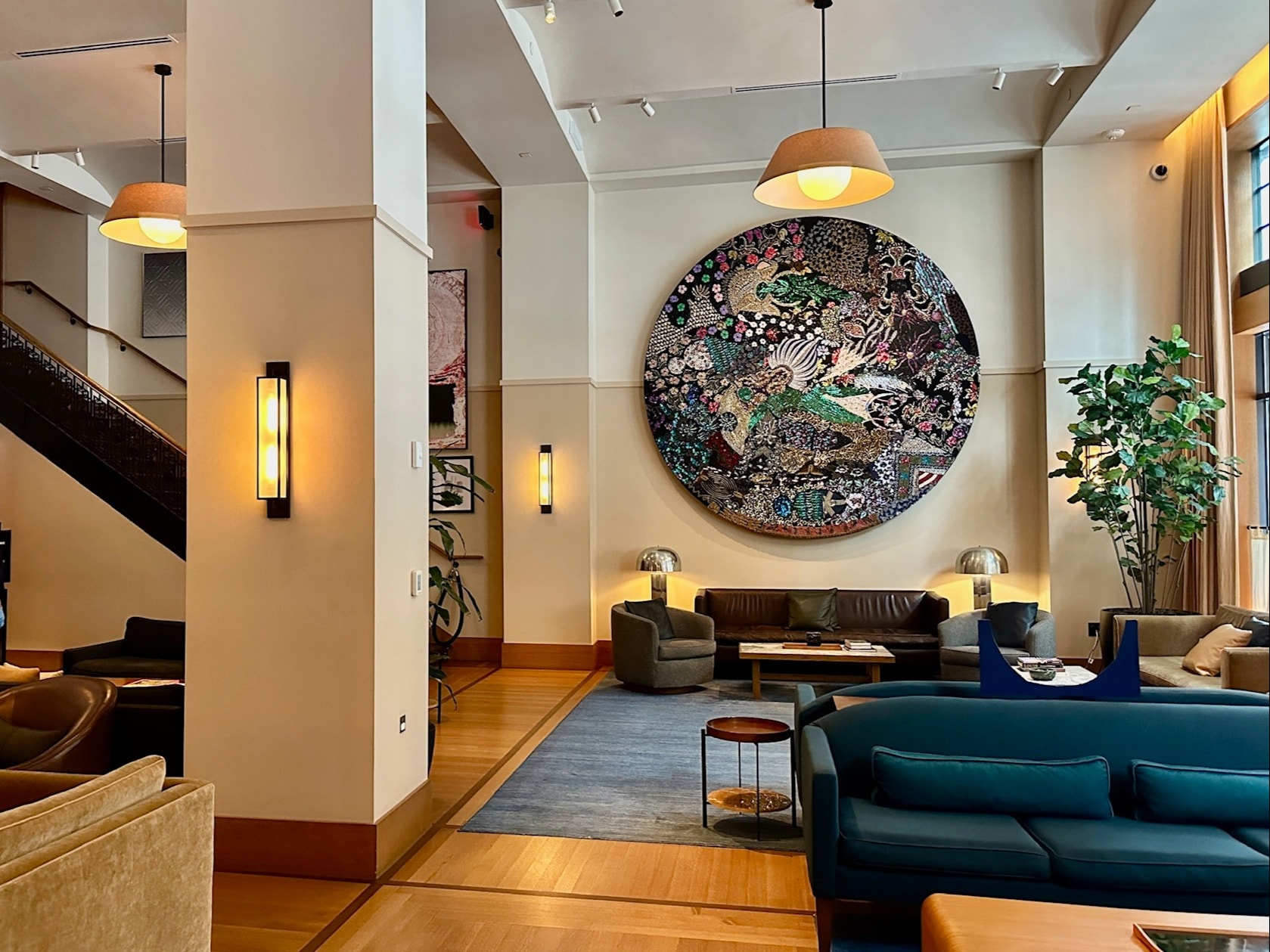 A lounge space in a hotel lobby with a round piece of art hung on the wall