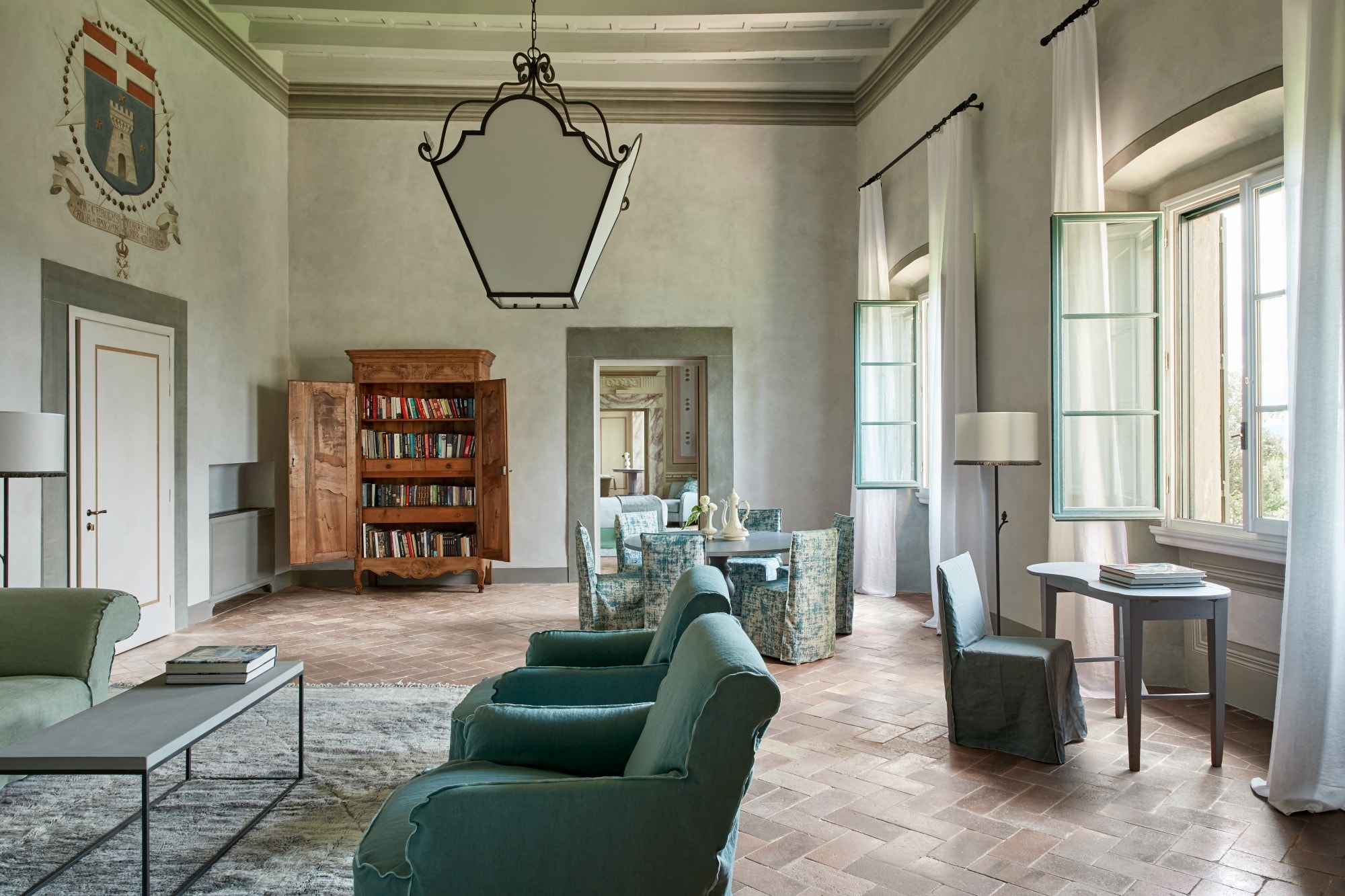 a luxe living room with green upholstered chairs and tall windows flooding the space with natural light