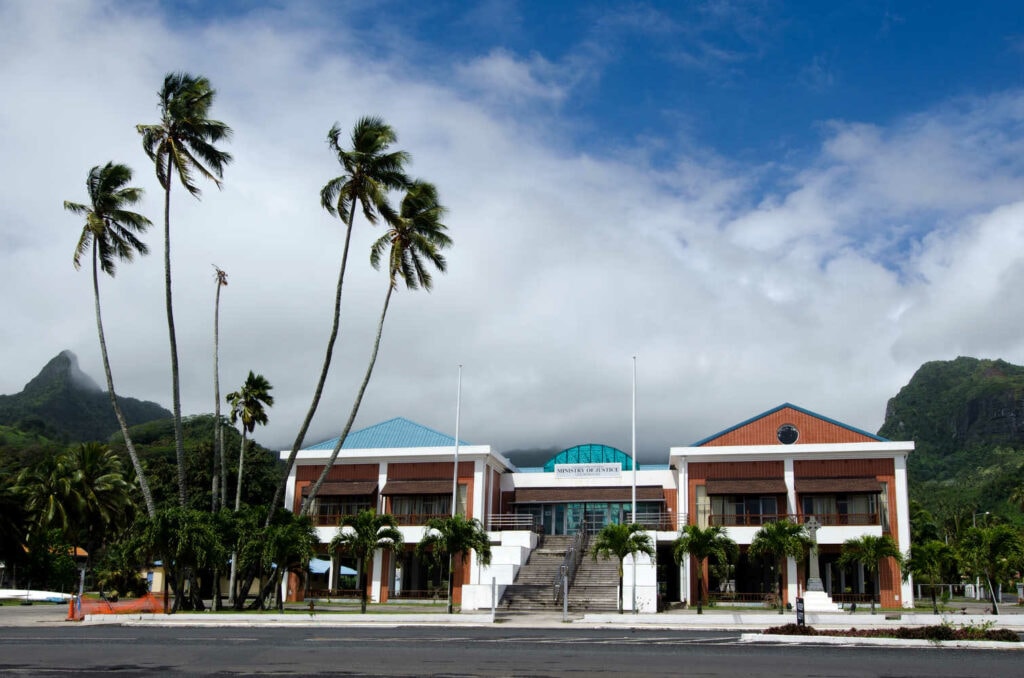 A brown building in Cook Islands and palm trees